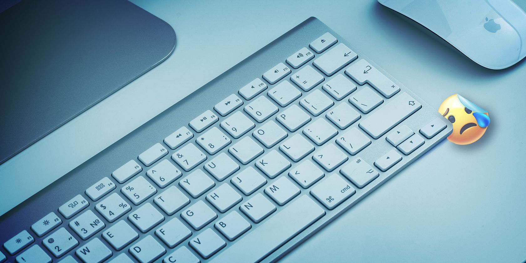 Magic Keyboard on a desk with crying emoji under it