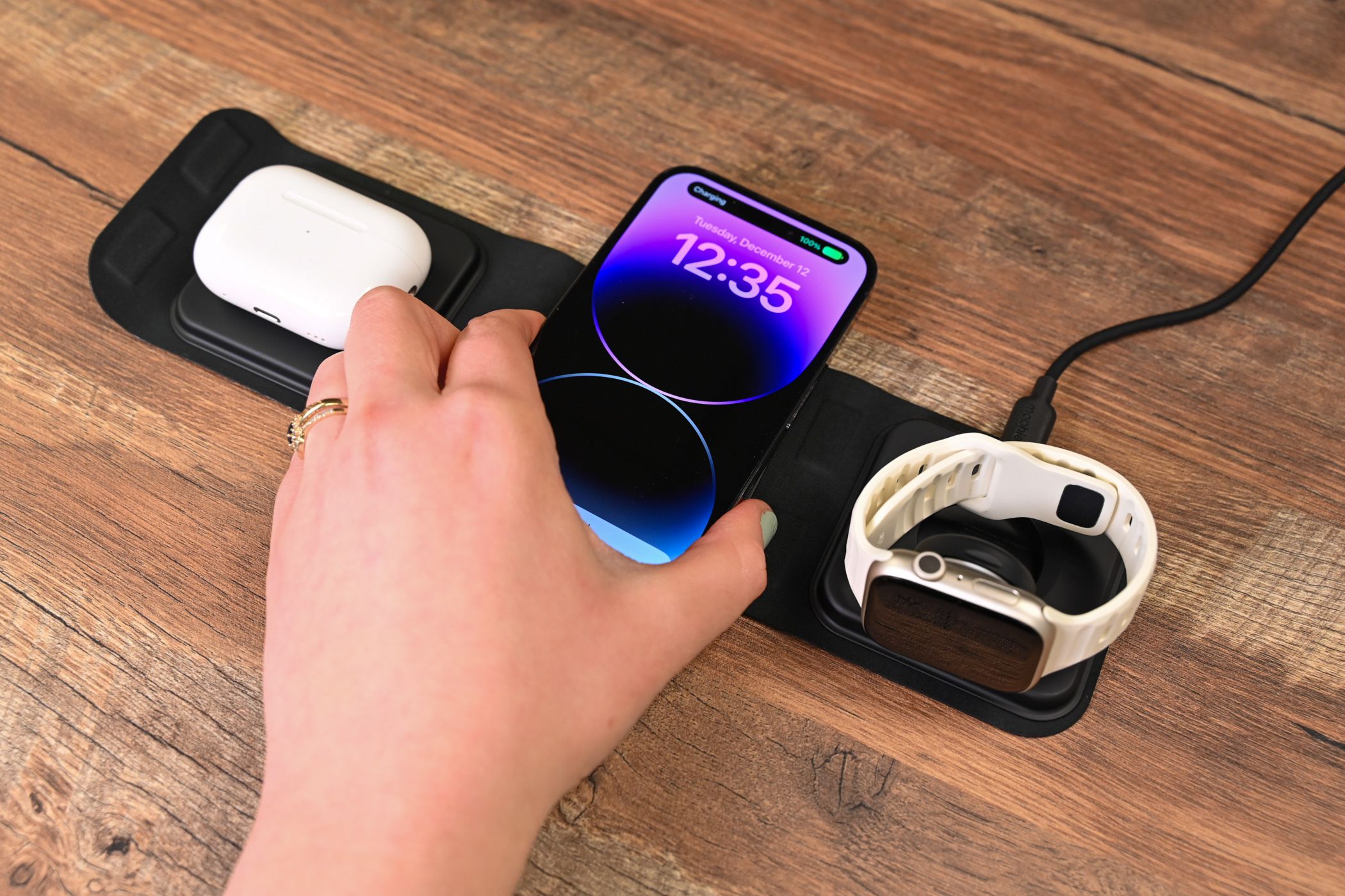 Pessoa colocando um iPhone no carregador de viagem Mophie 3 em 1 com MagSafe
