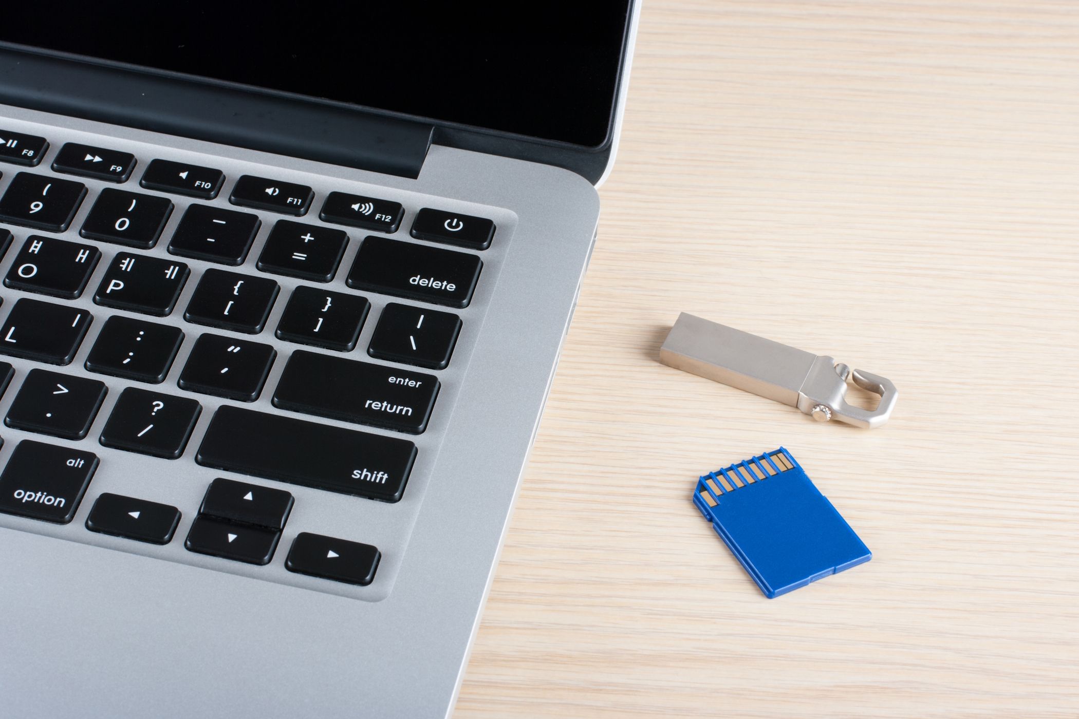 a MacBook next to a USB flash drive and an SD card on the desk