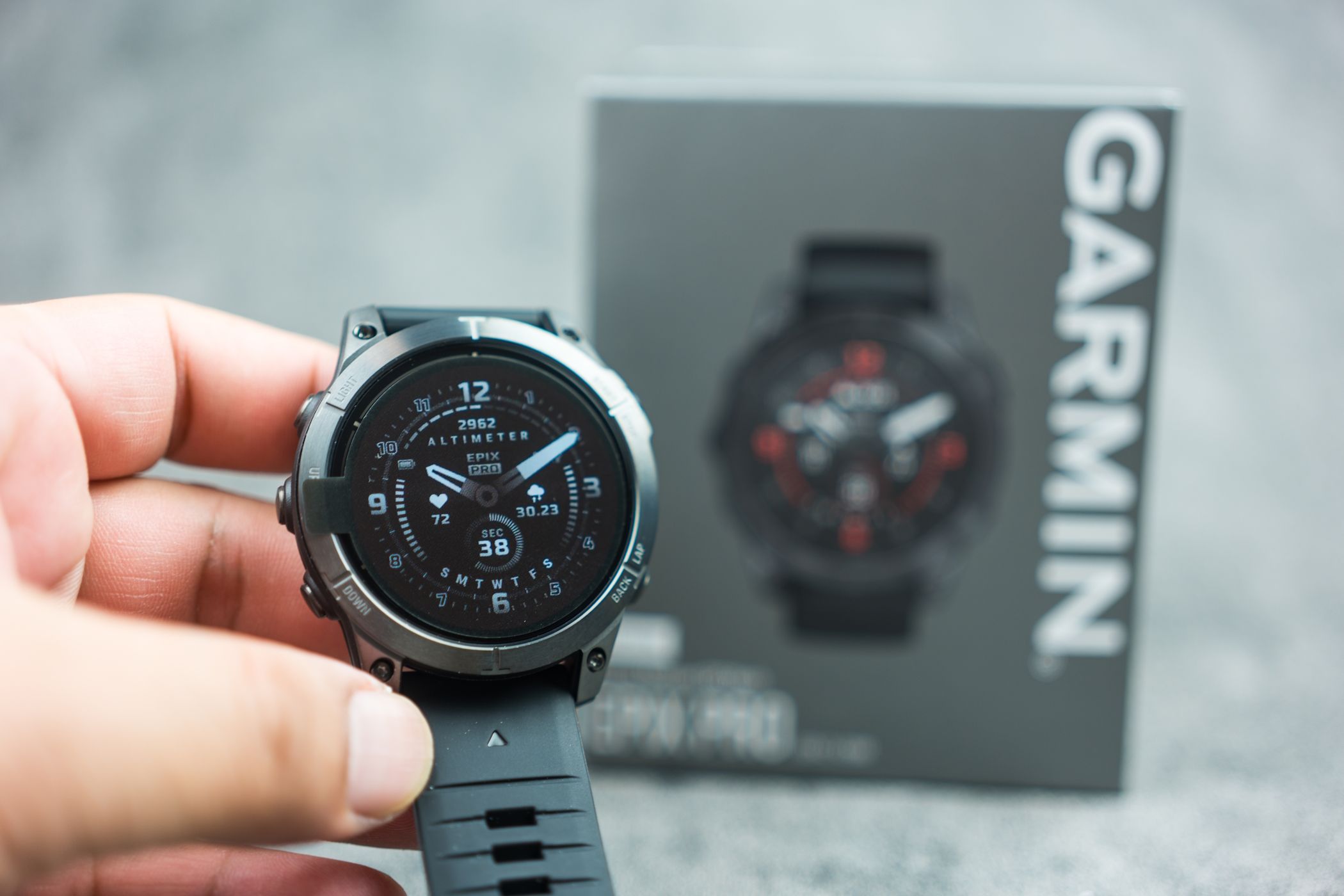 A man holding a Garmin epix Pro Gen 2 with its box in the background