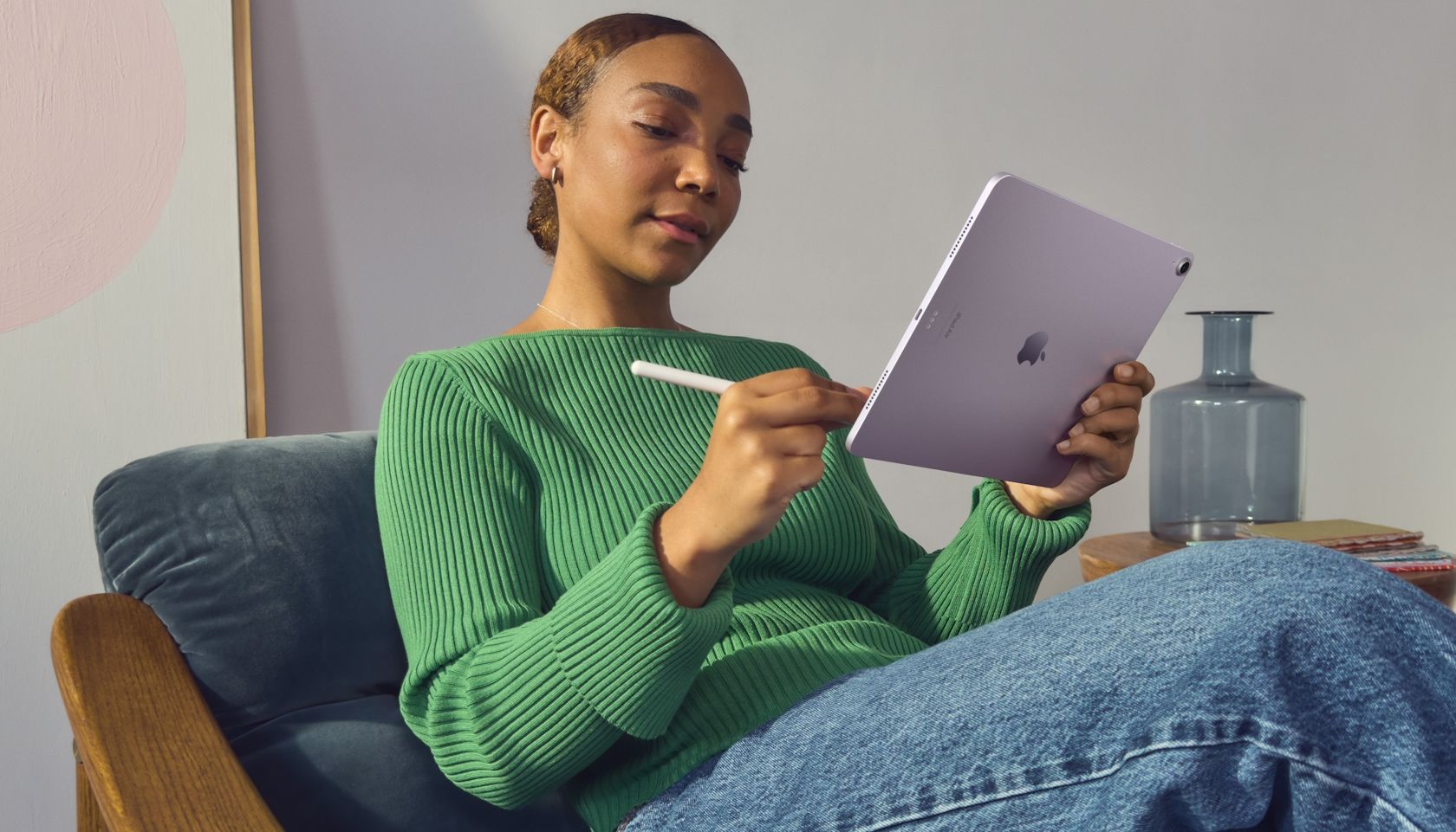 A woman holding an iPad Air with one hand while using an Apple Pencil
