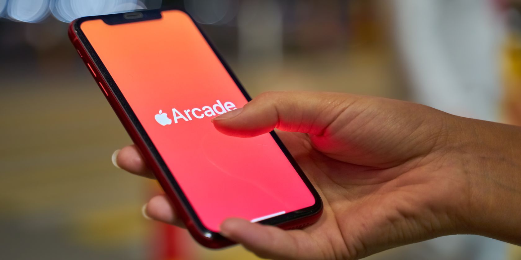 a woman holding an iphone with the apple arcade logo