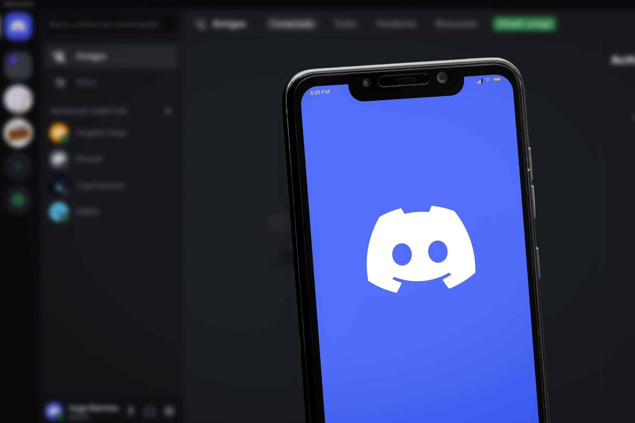 discord logo on a smartphone in front of a screen displaying the discord app