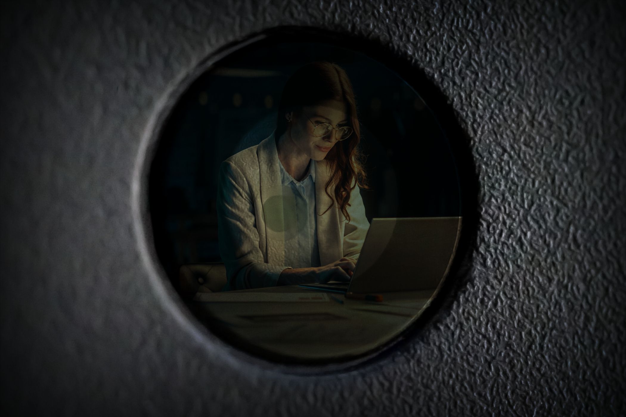 A person working that is seen through a reflection on a webcam