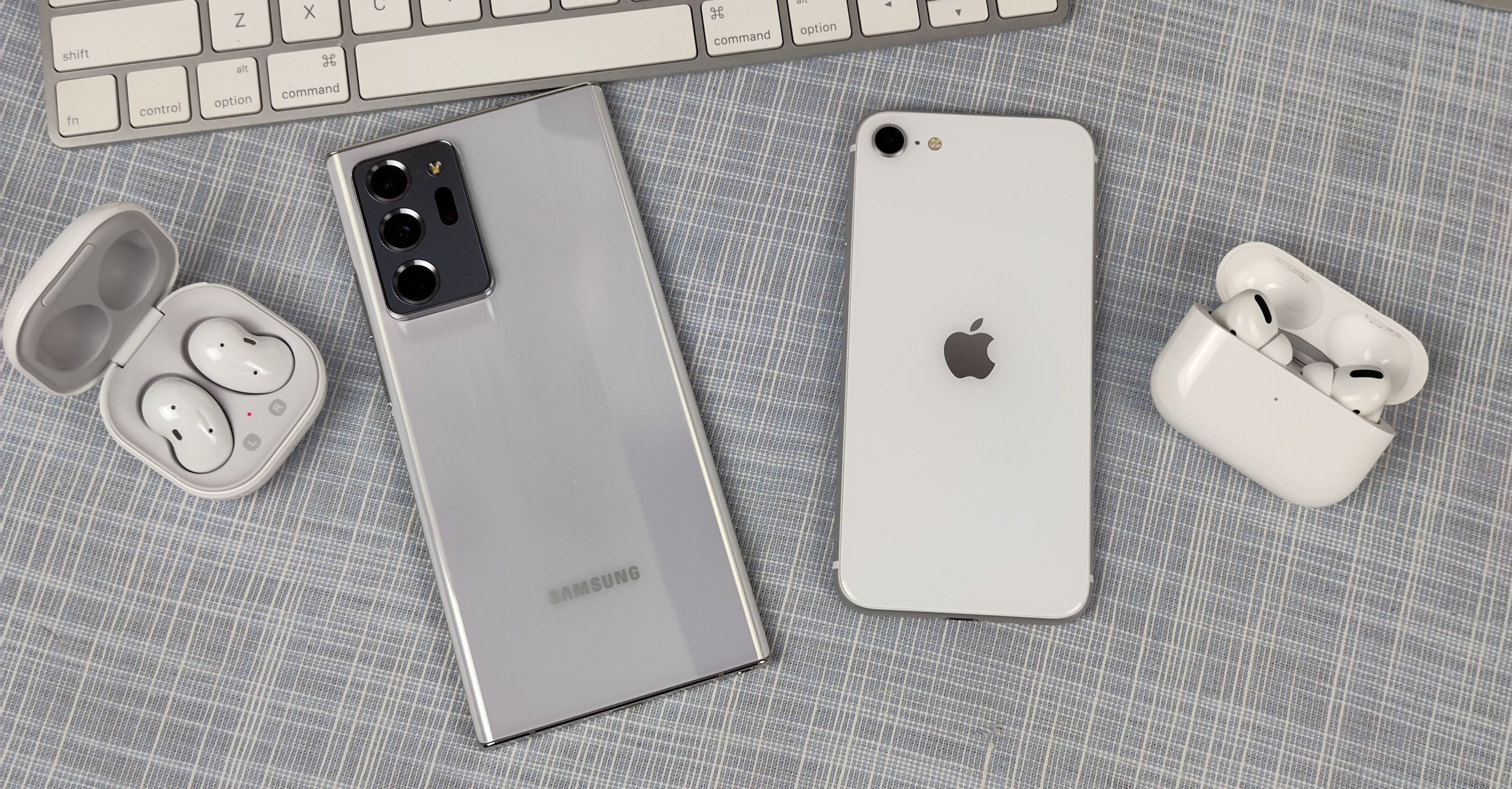 iPhone e telefone Samsung Galaxy próximos um do outro com Galaxy Buds e AirPods Pro próximos a eles