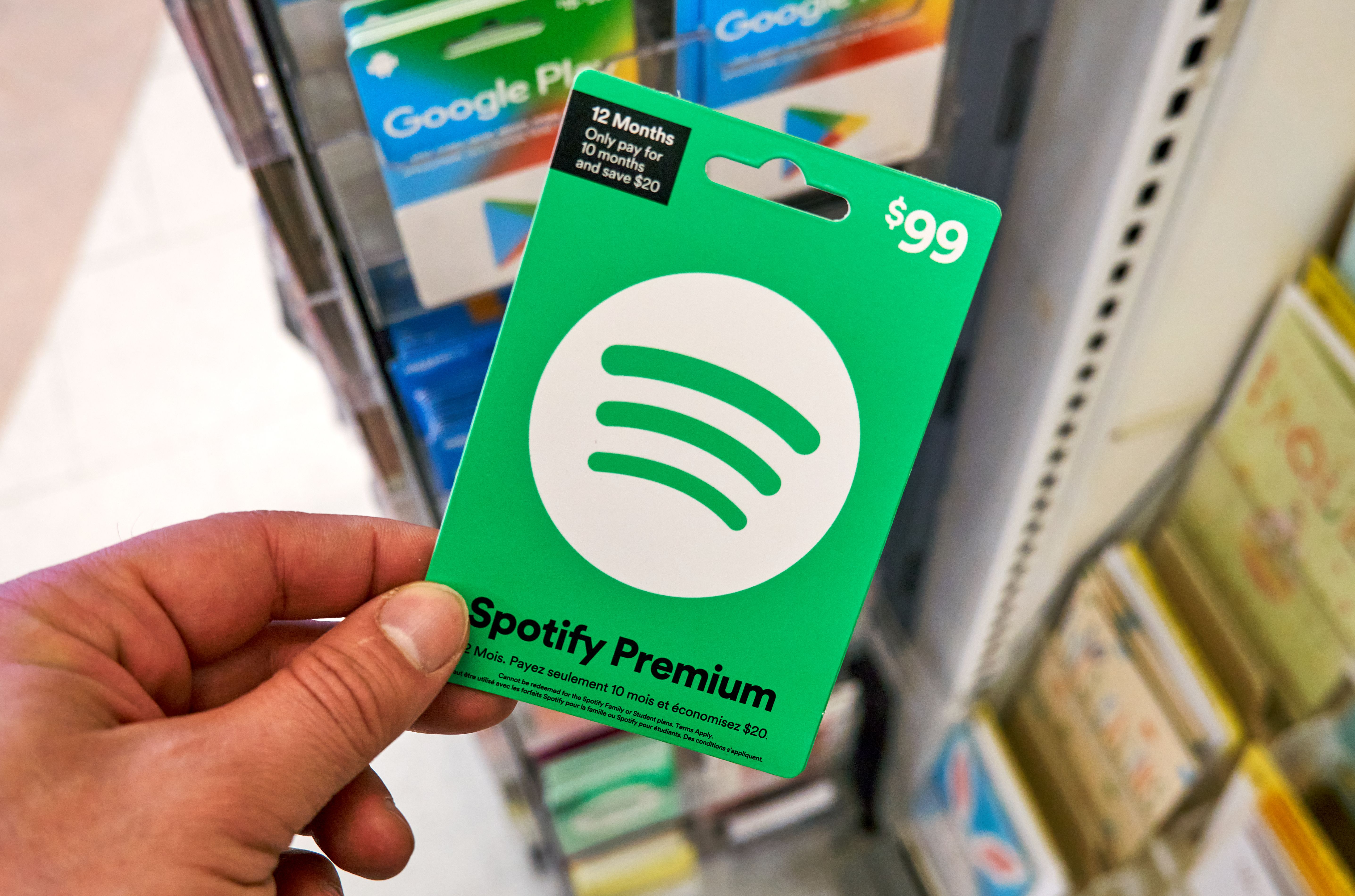 Someone holding a Spotify gift card in a shop