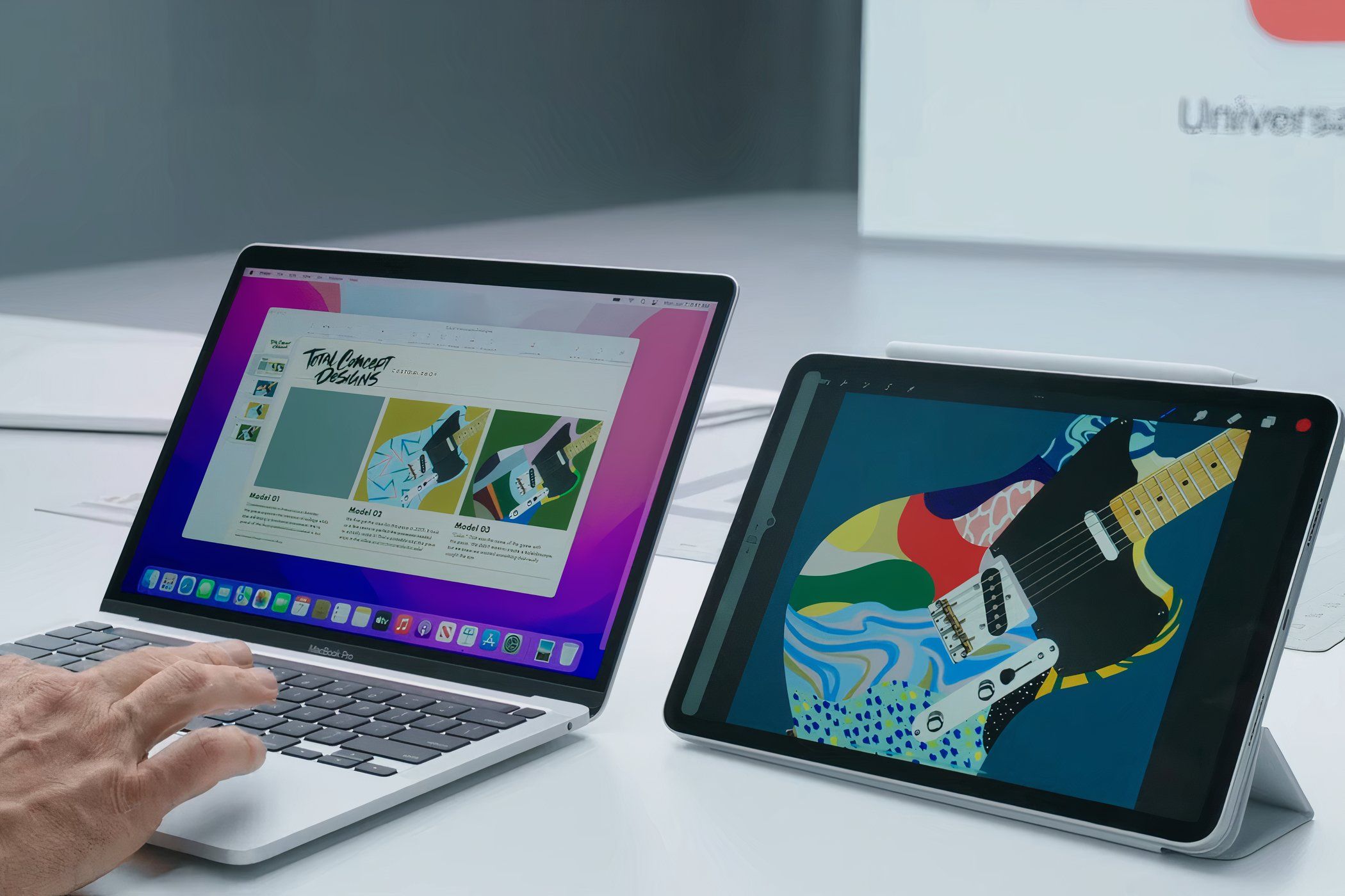 A man typing on a MacBook Pro with an iPad Pro nexst to it
