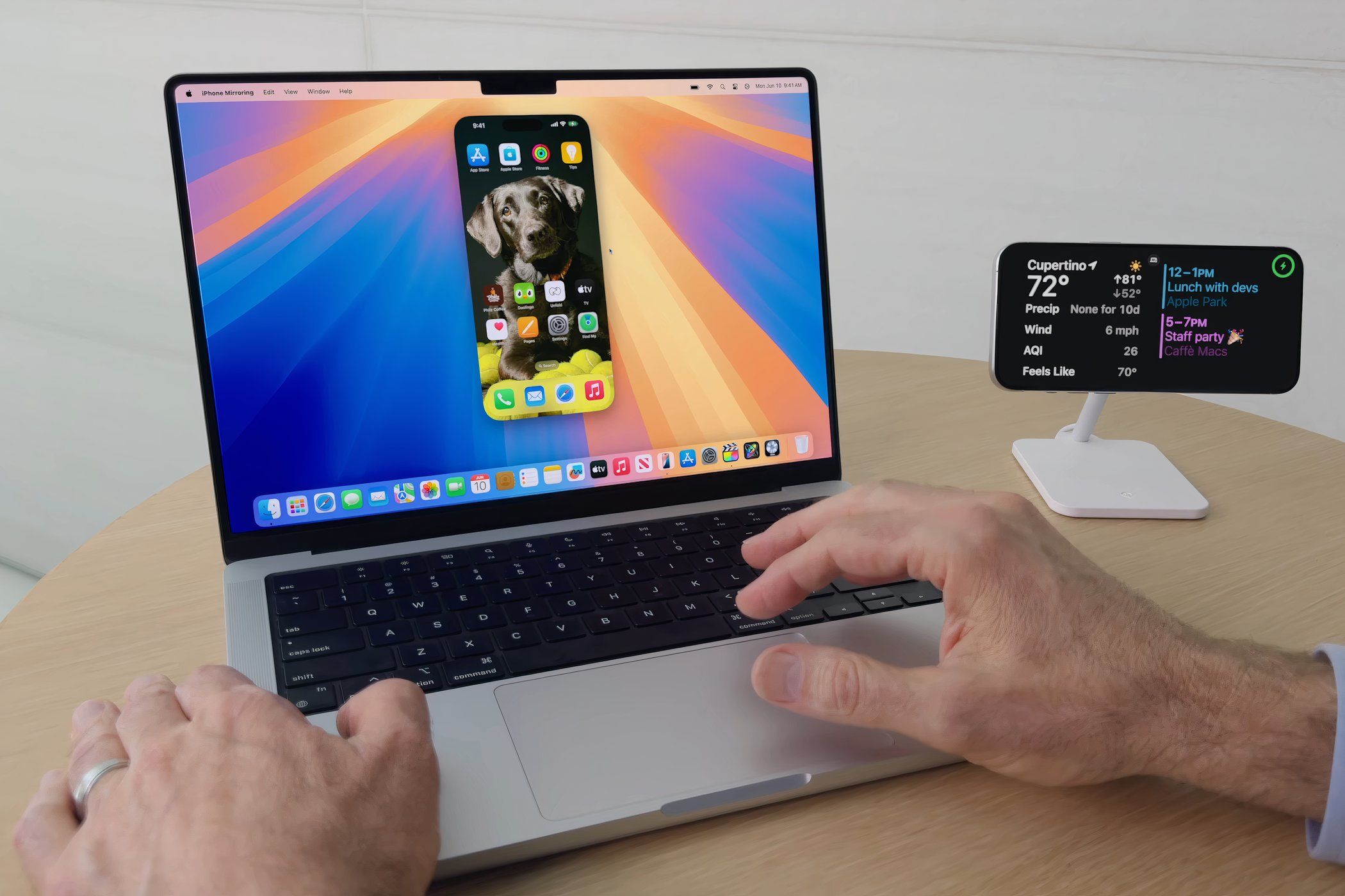 A man using a MacBook Pro running macOS Sequoia with the iPhone Mirroring feature