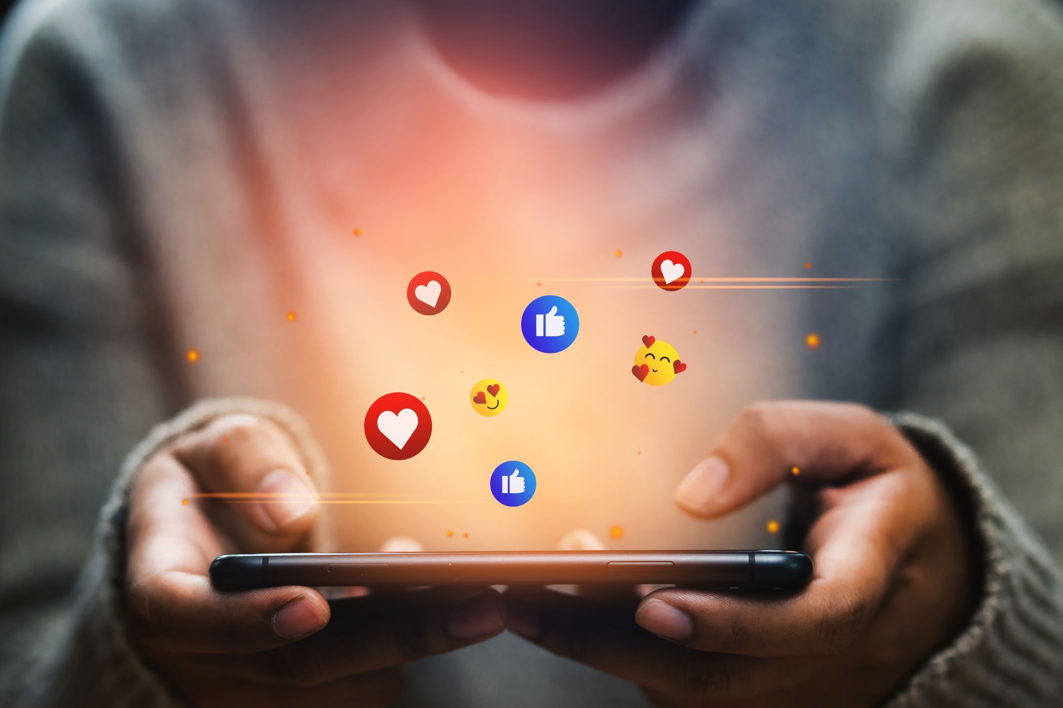 a person holding a smartphone with social media engagement icons floating above it