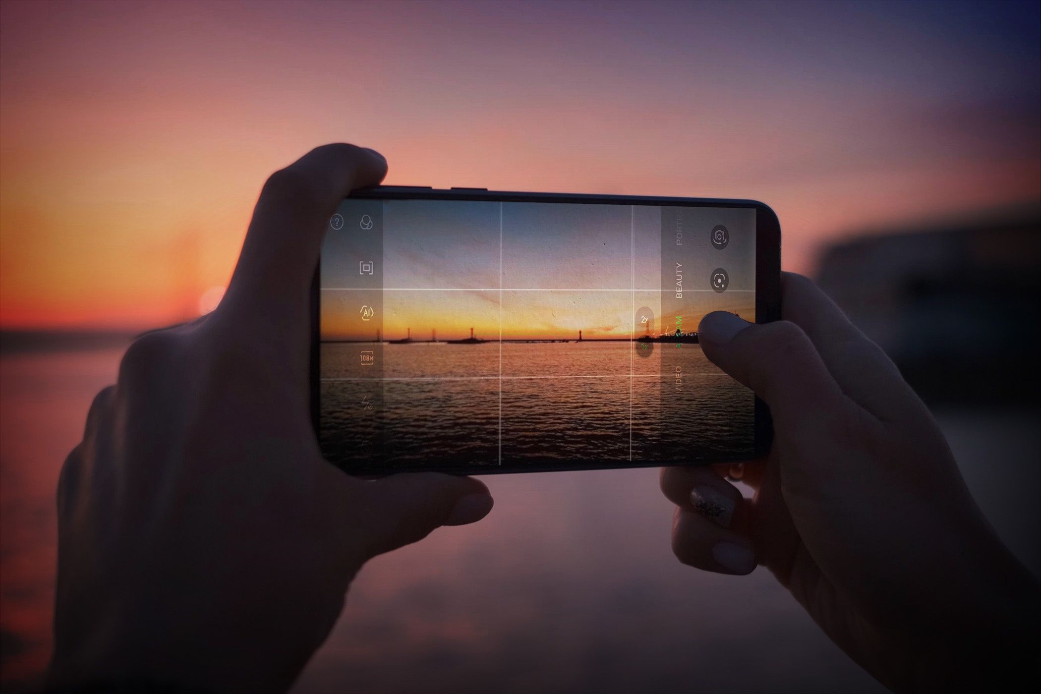 Person using a latest smartphone to capture a sunset, framing the scene with camera gridlines on the screen.