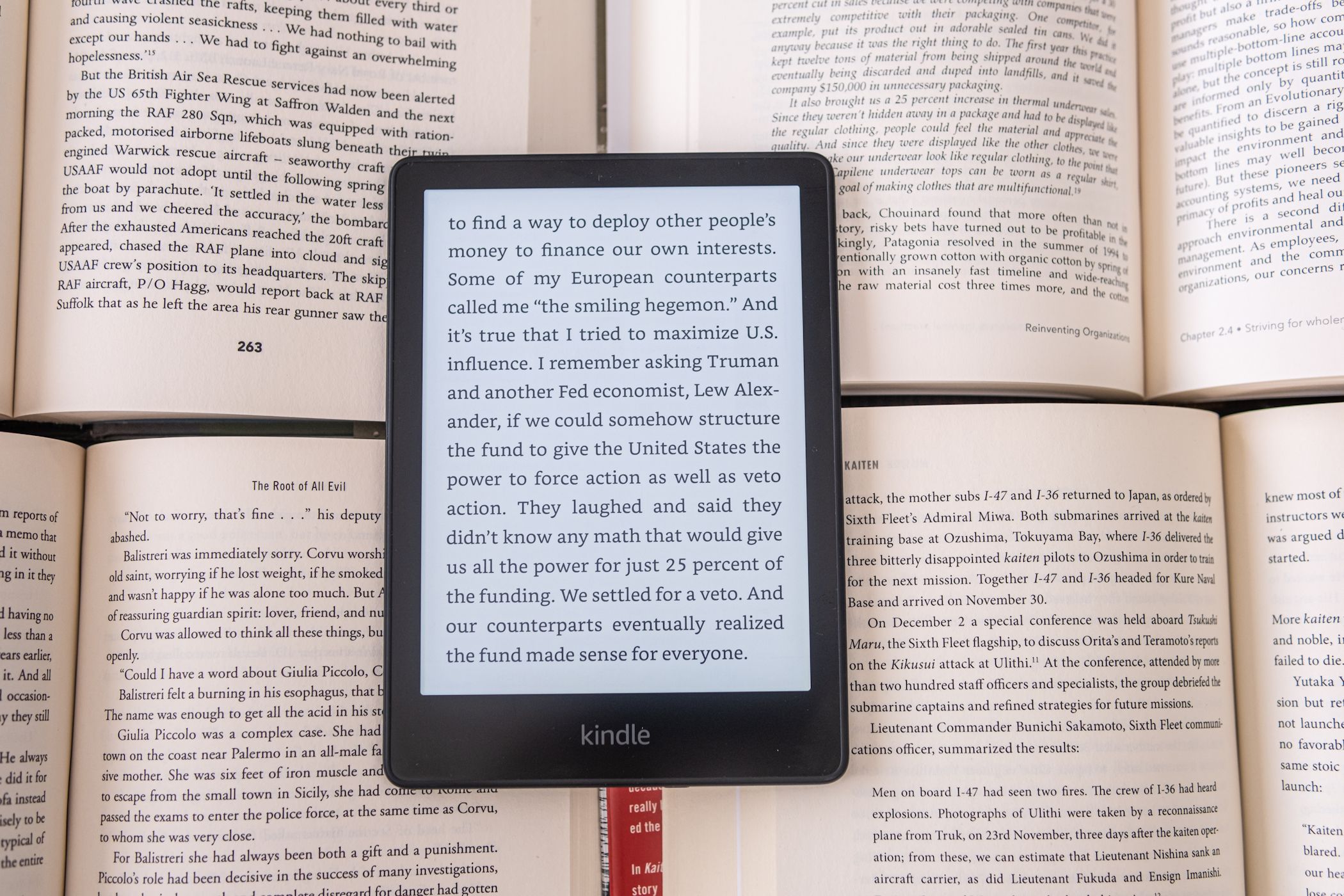 kindle ereader on pile of open books displaying text
