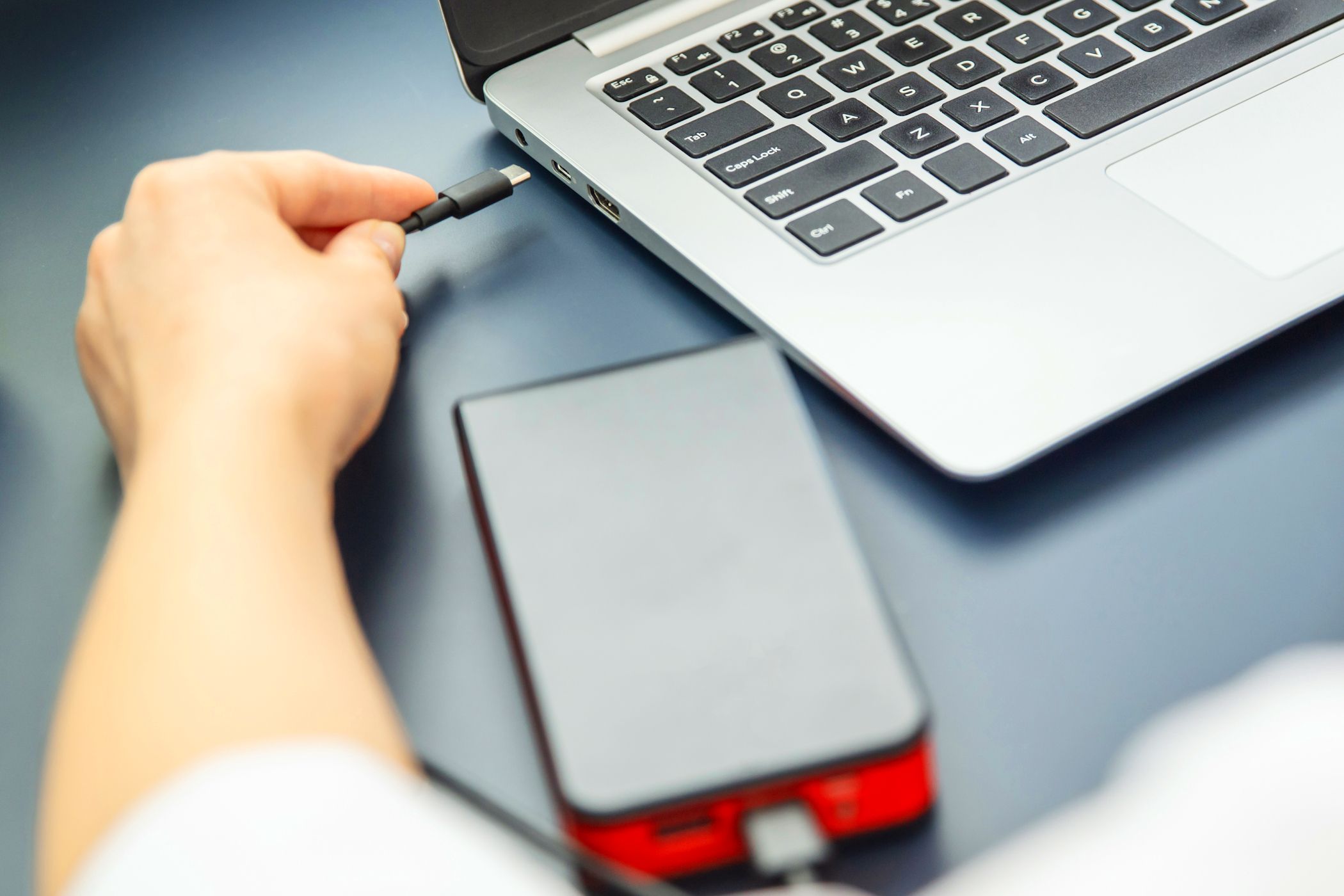 woman pluggin usb c cable into laptop with power bank