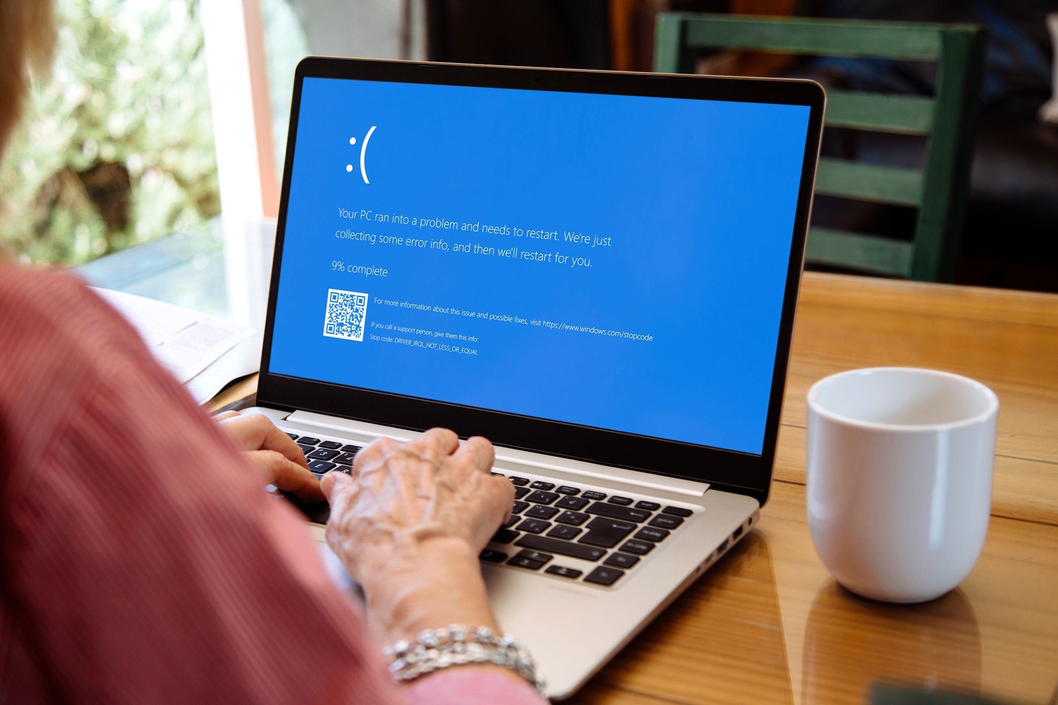 A Blue Screen of Death error appearing on a Windows laptop while a woman is using it