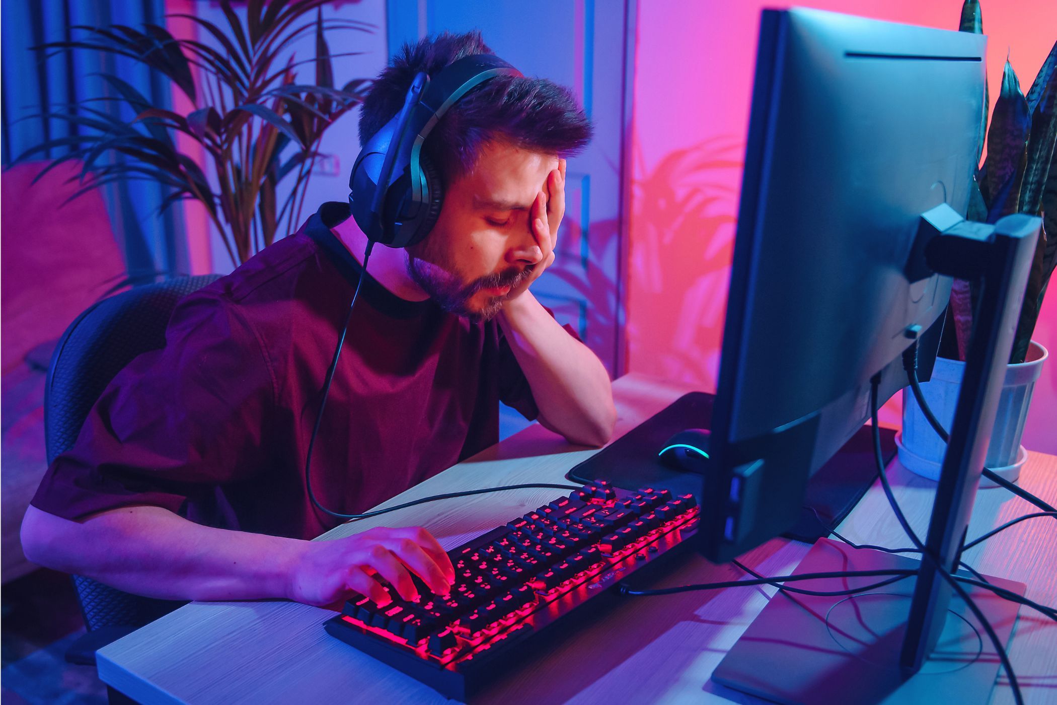 Disappointed PC gamer with hand over face in front of computer