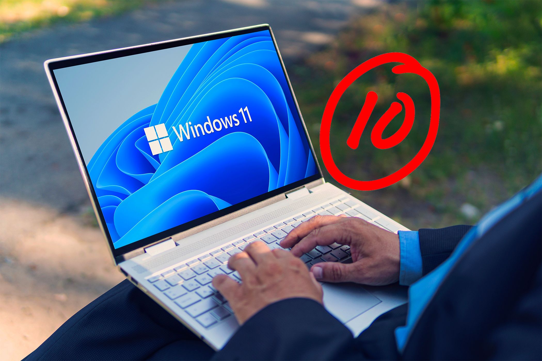 10 score next to a laptop running Windows 11 while a man is typing on its keyboard