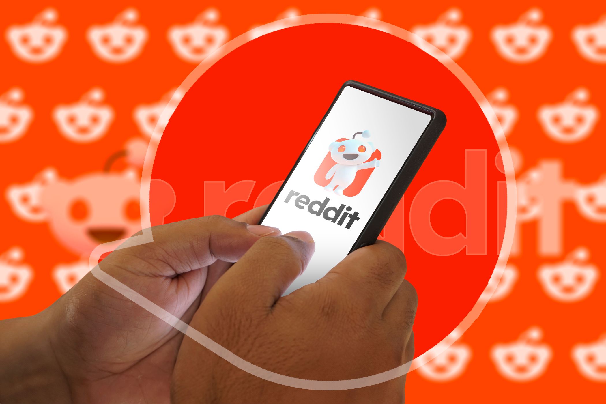 دستی که گوشی با آرم Reddit در دست دارد.