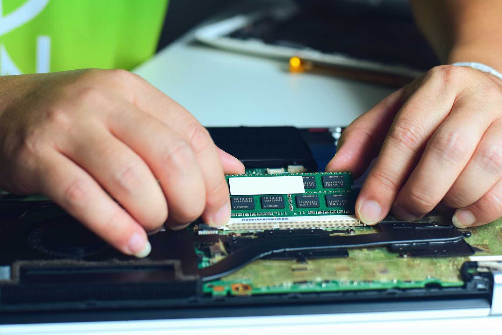 A technician swapping the RAM in a laptop