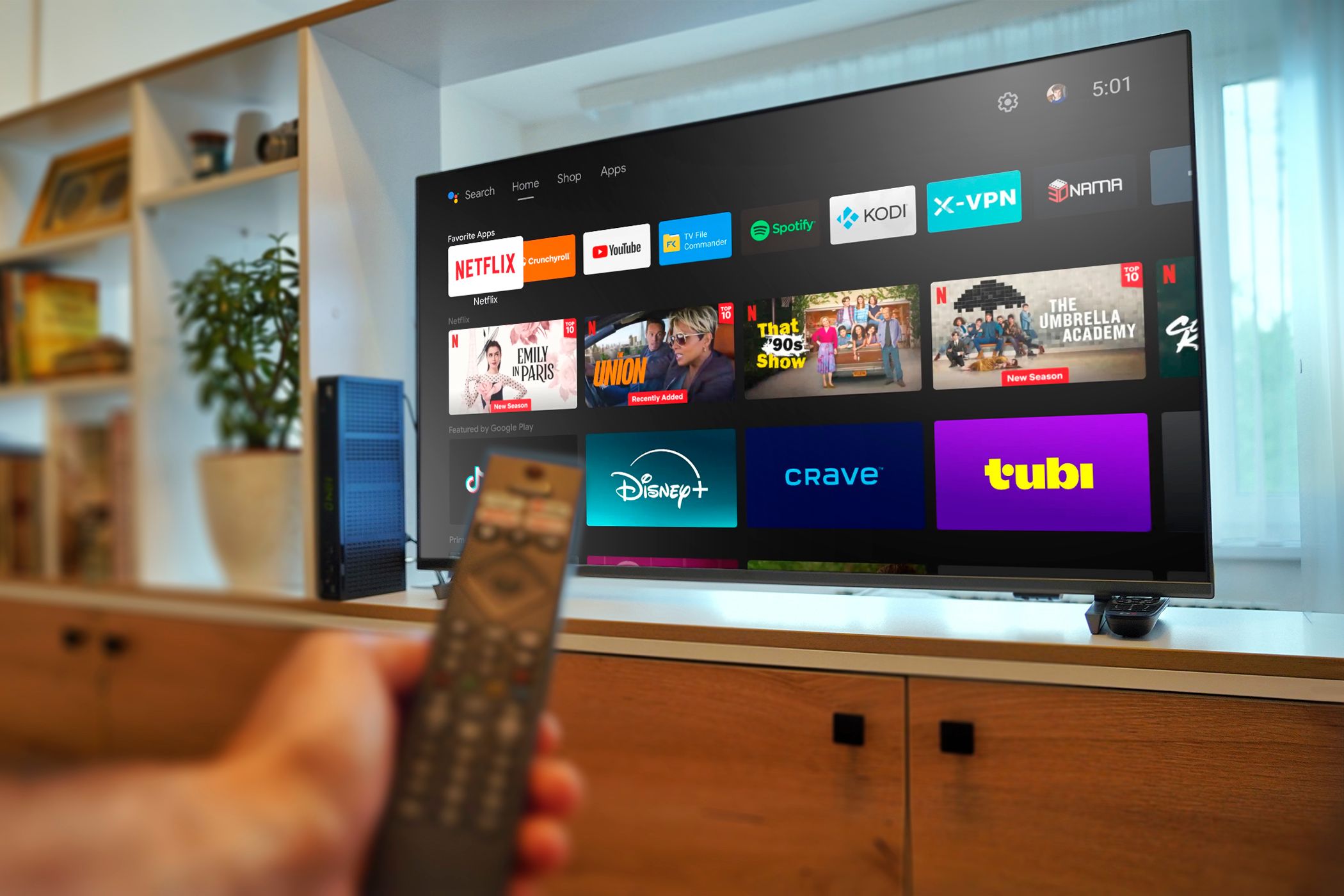 An Android TV with a hand holding a remote control.