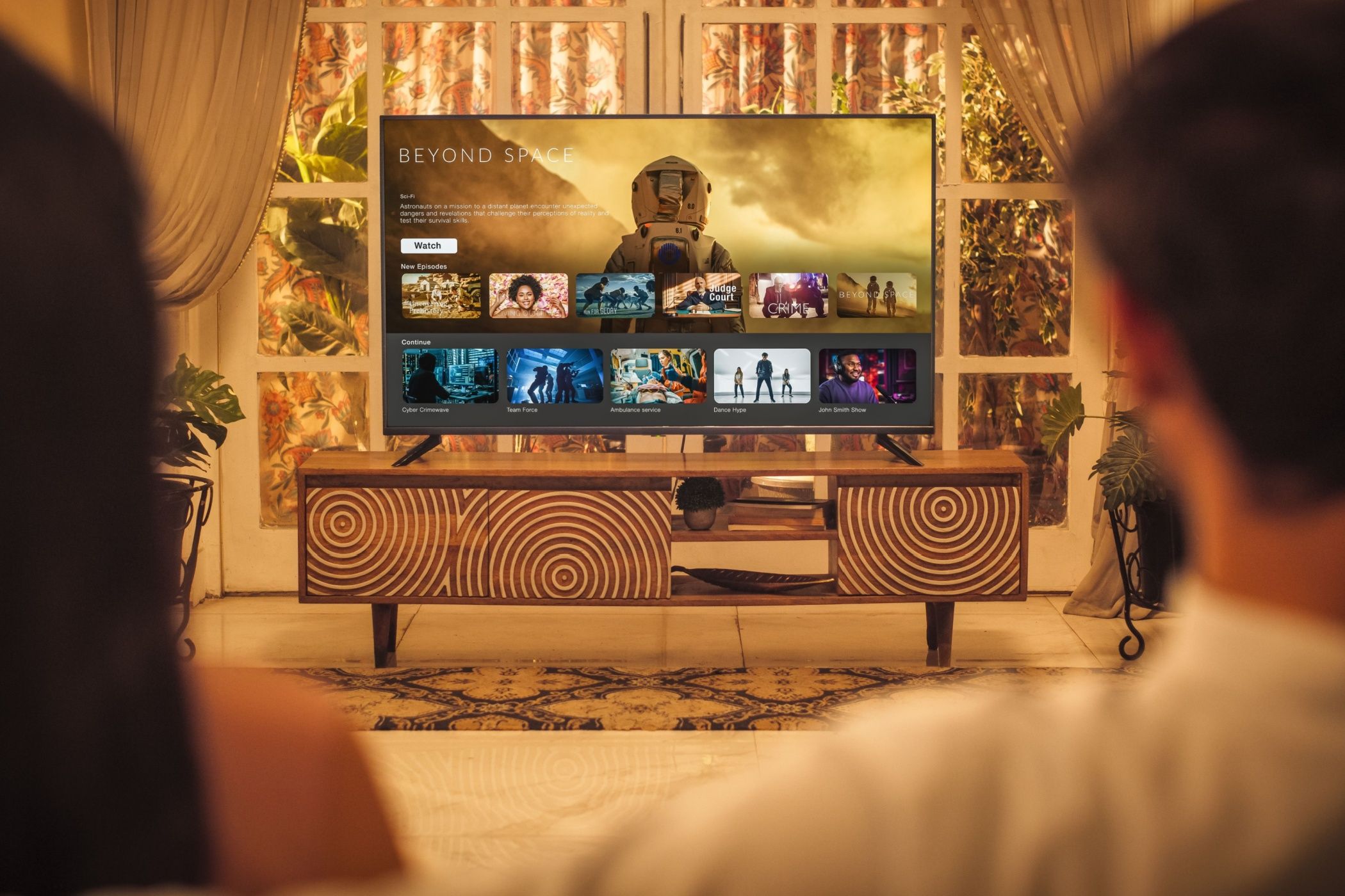 Back View of Young Couple Watching TV while Sitting on a Couch in the Living Room