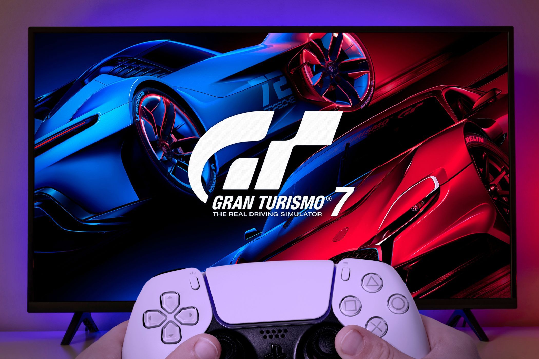 gran turismo 7 on a screen with a ps5 controller held in front