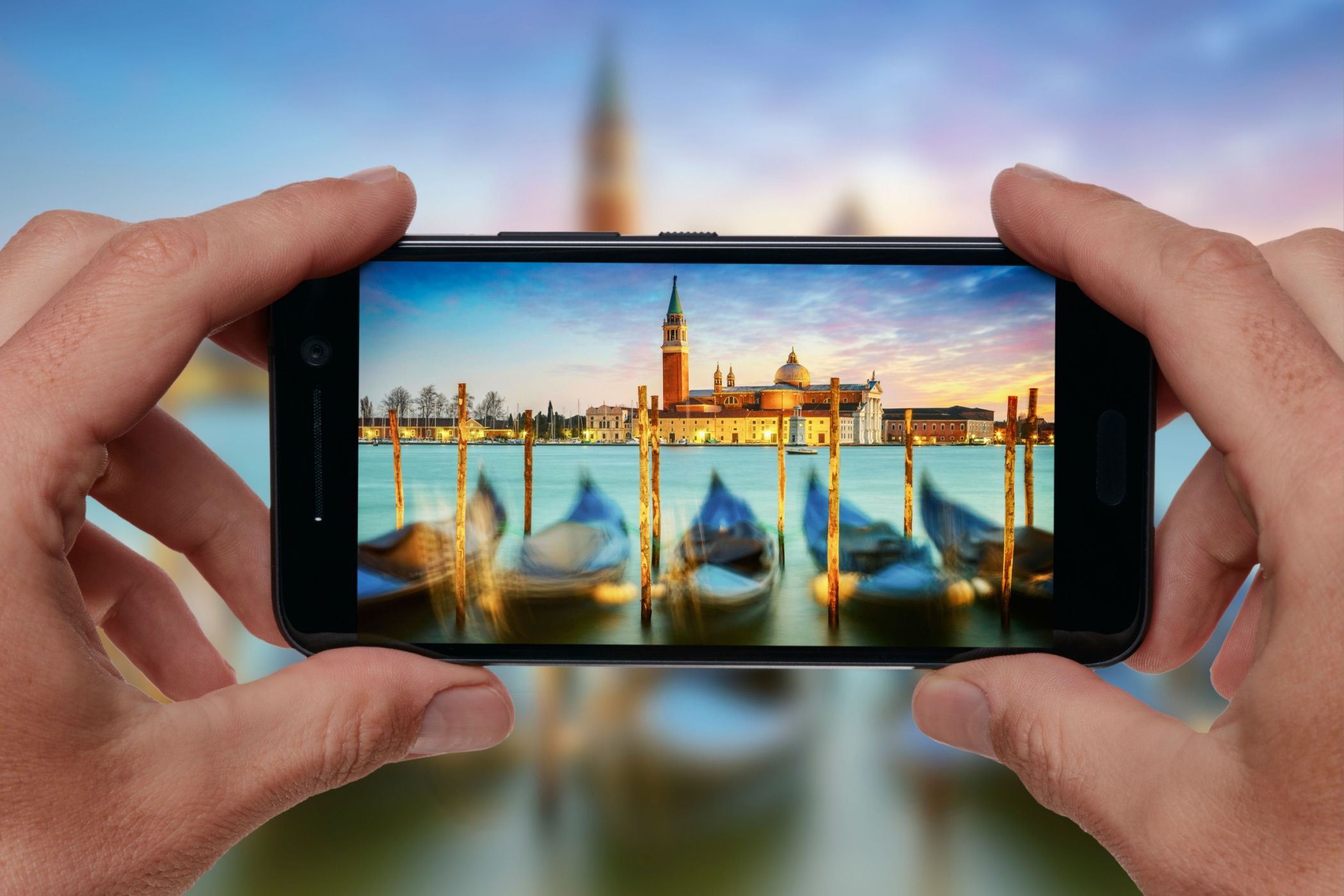 Hands taking picture of Venice, Italy in sunset lights with smartphone camera