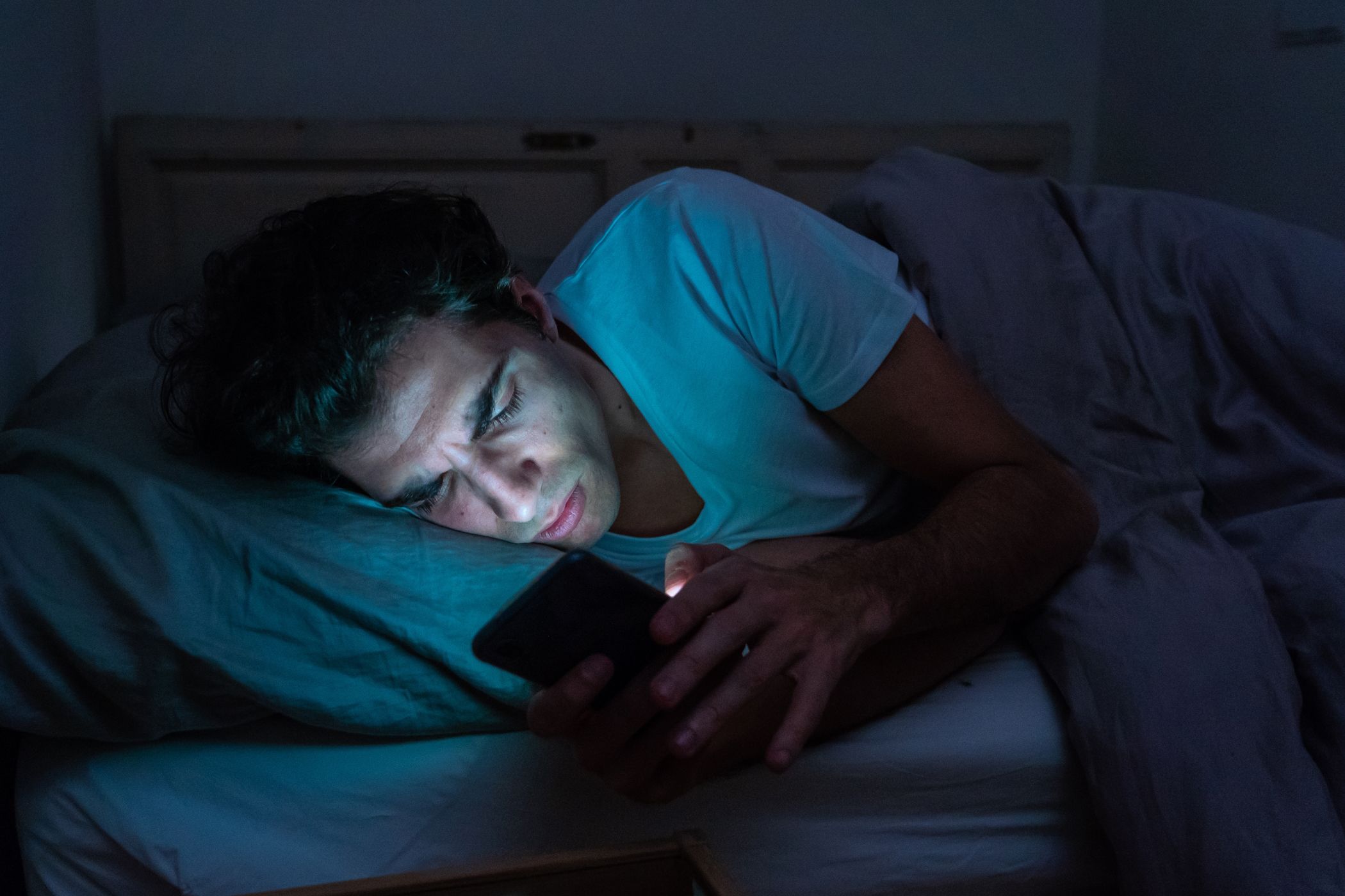 A man using a smartphone in bed