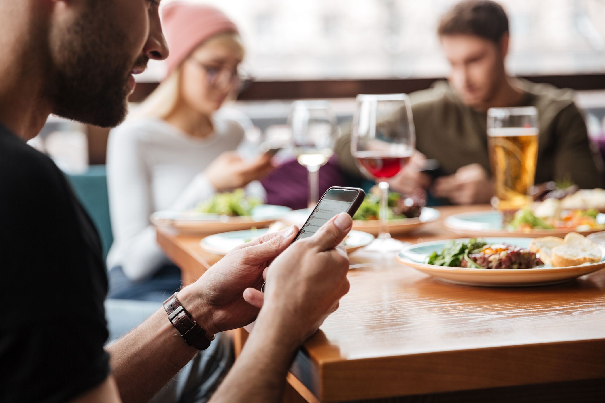 A man using his phone in front of his friends while eating