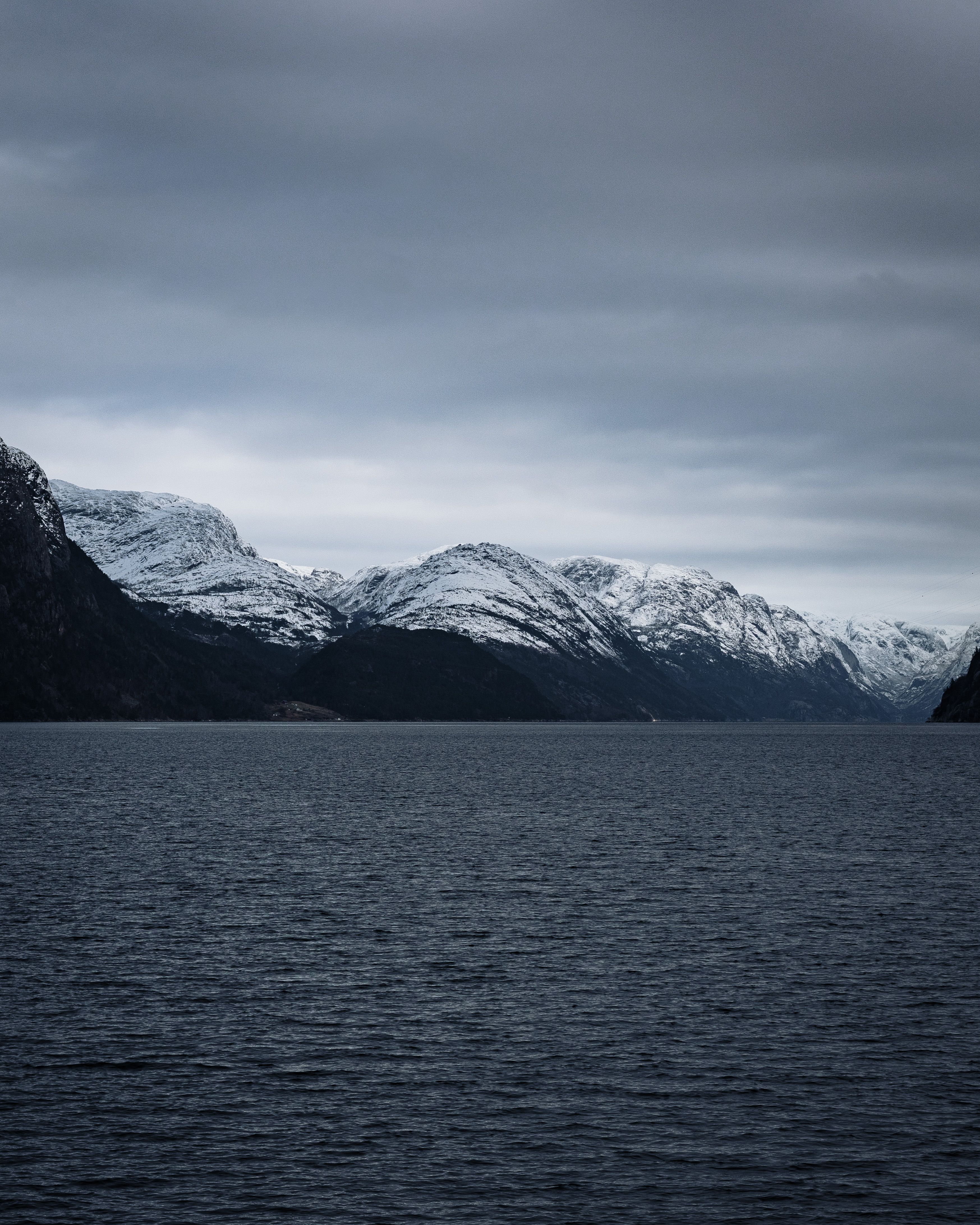 a photo of mountains lining a fjord, taken from a boat