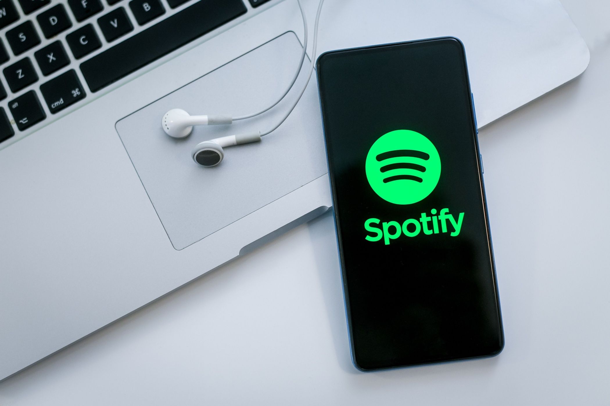 Spotify روی صفحه نمایش گوشی هوشمند با لپ تاپ و هدفون در پس زمینه