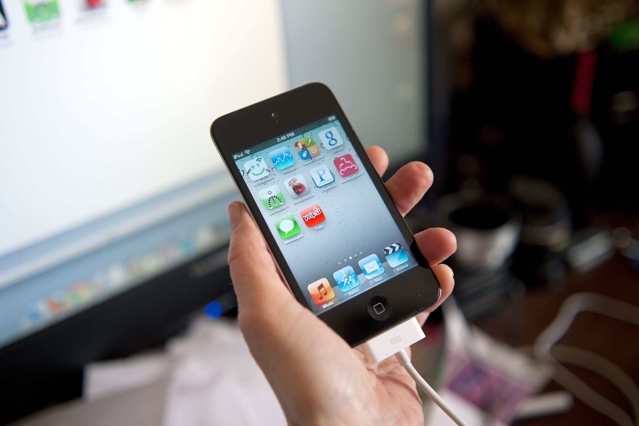 person holding an old ipod touch with charging cable