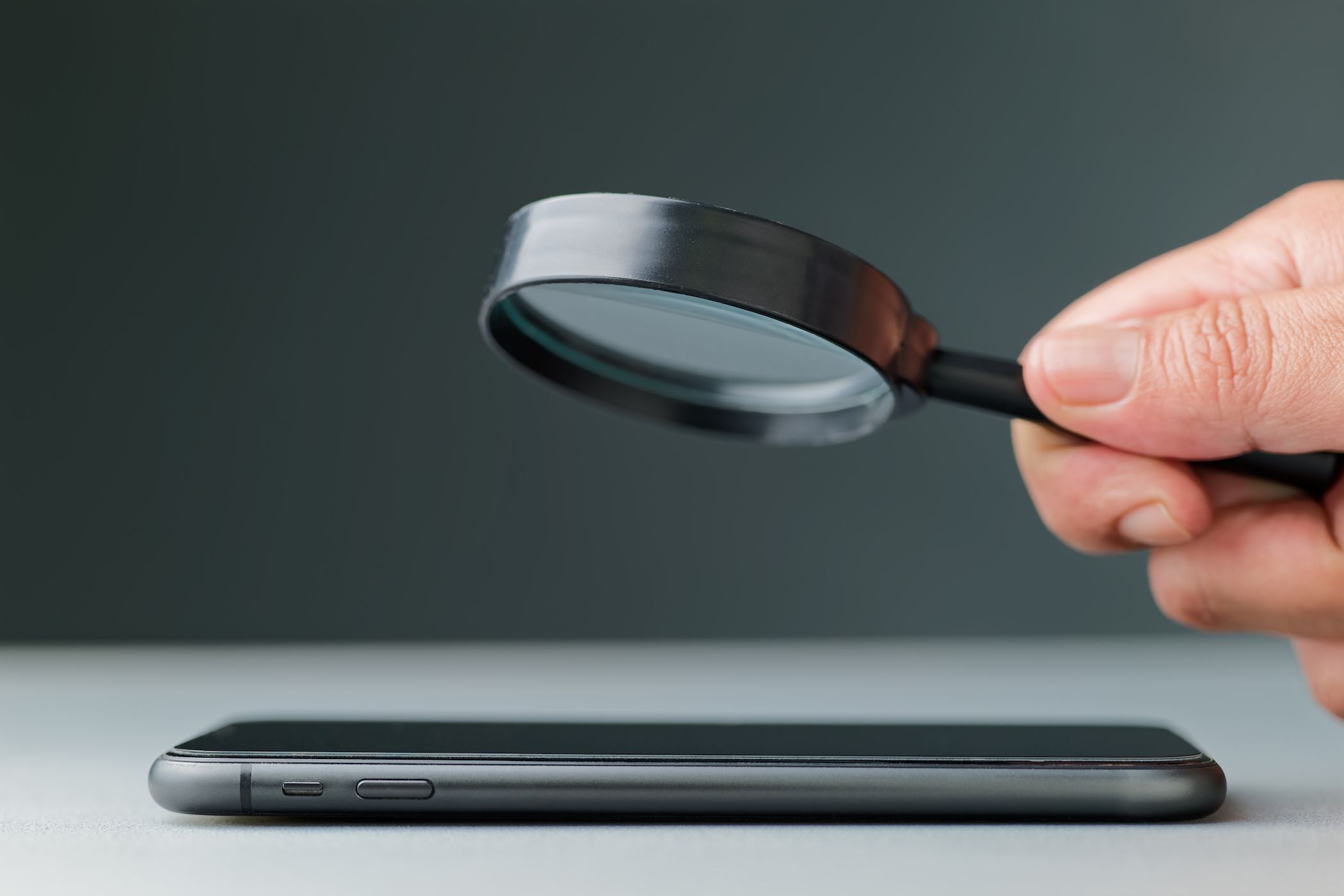 person looking at smartphone with magnifying glass