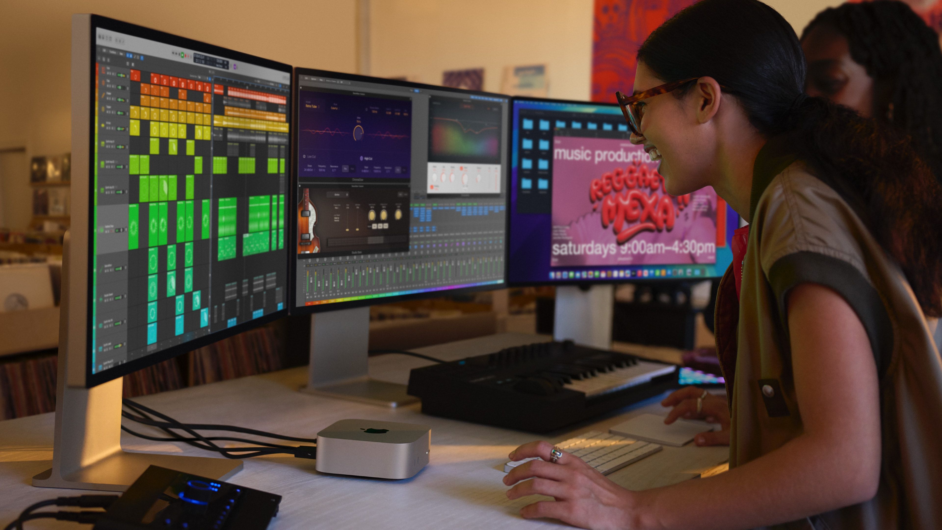 A young woman works on a mac mini hosting three displays