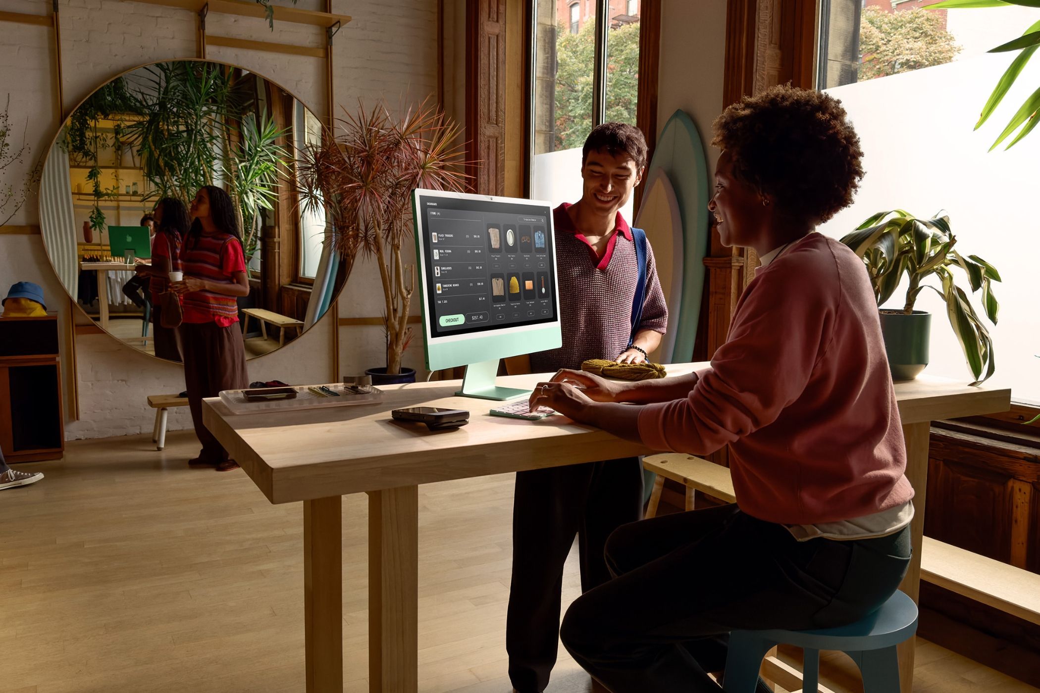 iMac Kept On a table opposite from a window with a lady using the machine