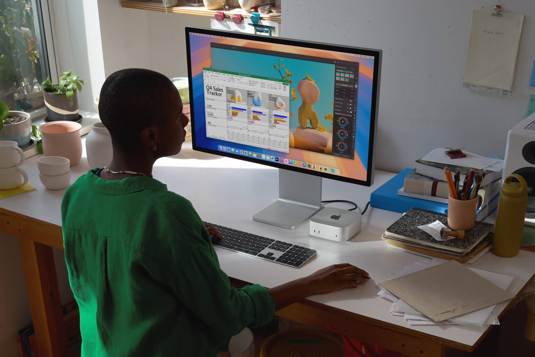 A young man works at his desk on a mac mini
