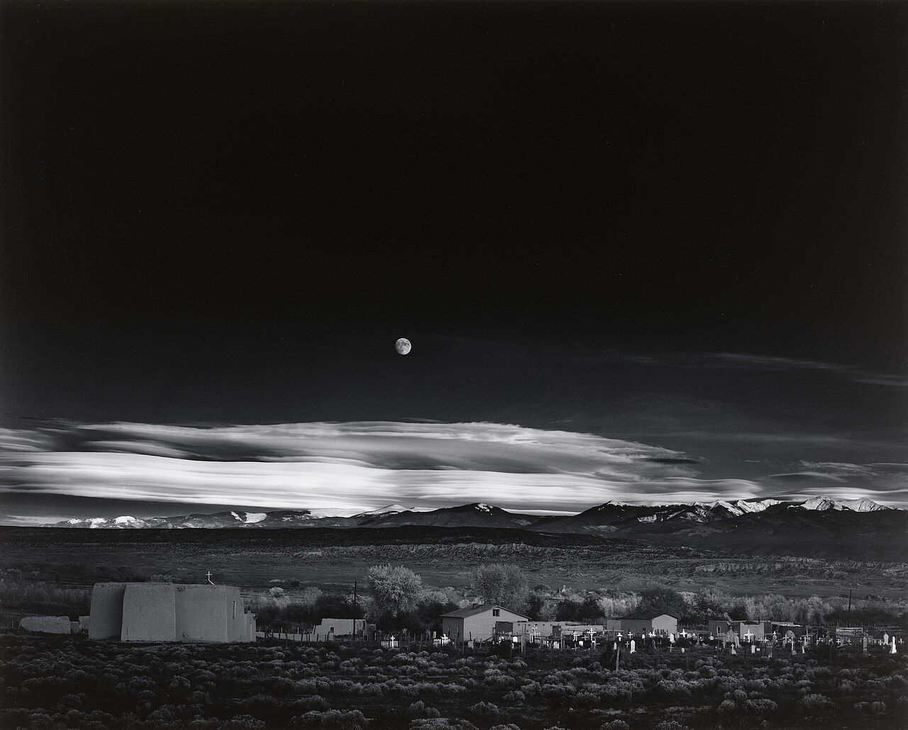 Photograph depicting moon above a dark desert city