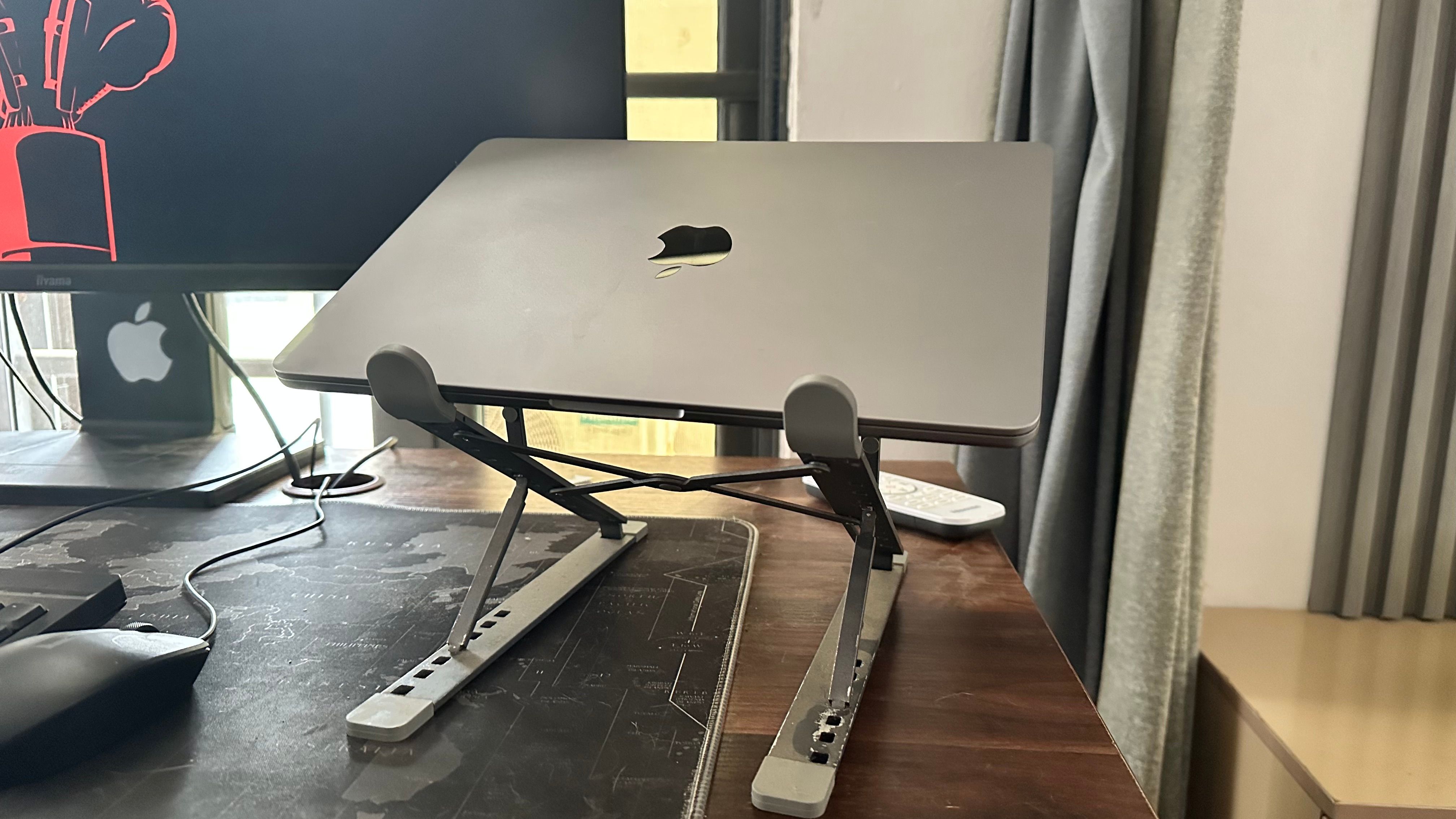 MacBook on a laptop stand next to a monitor