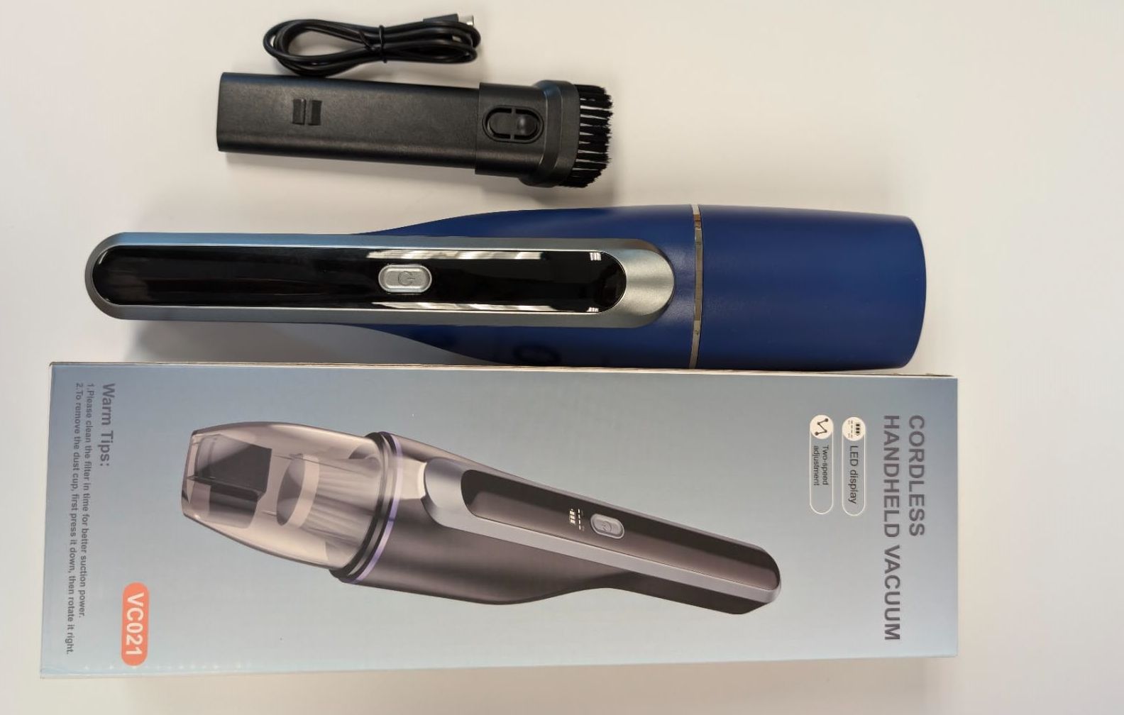 A blue cordless handheld vacuum cleaner with accessories and packaging.