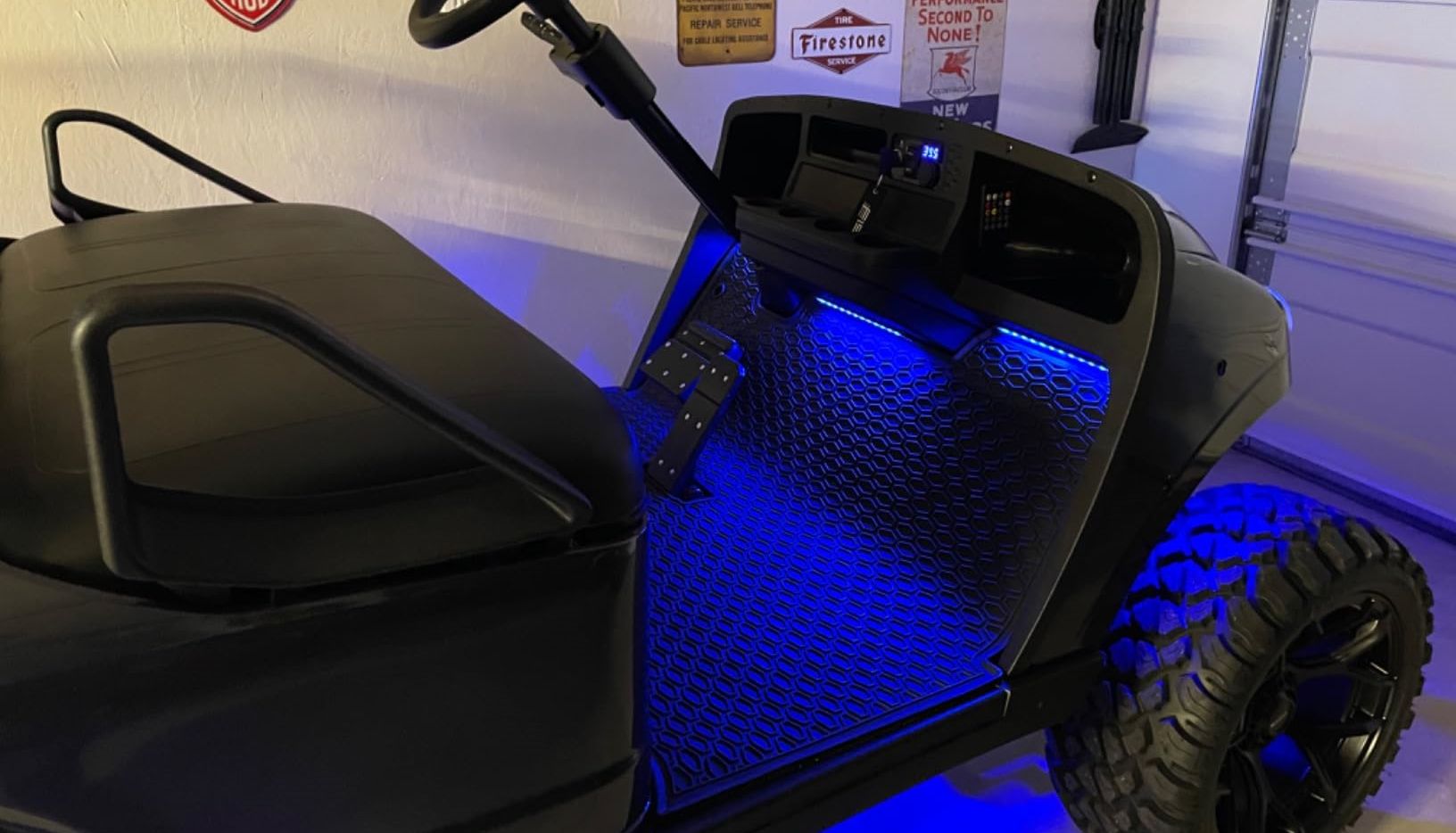 A black golf cart with blue LED lights installed on the floorboard and under the cart.