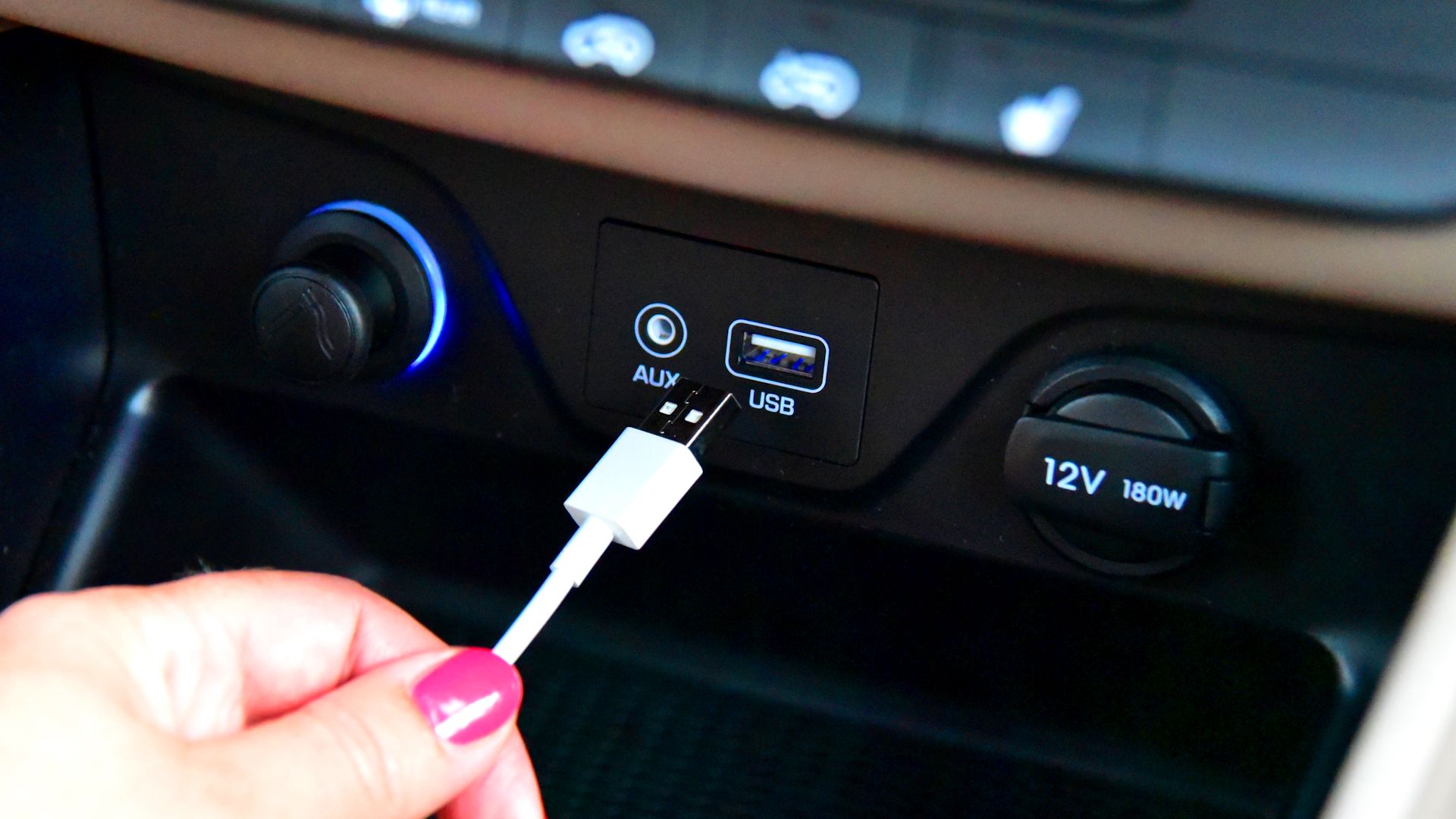 person pluggin usb cable into in car usb port