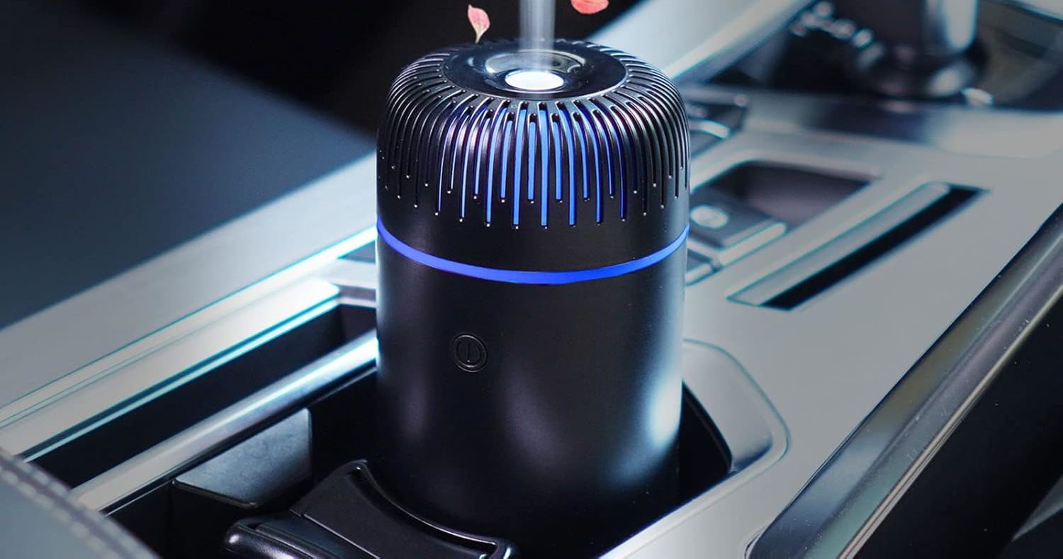 A small, black, cylindrical car humidifier placed in the cup holder of a car.
