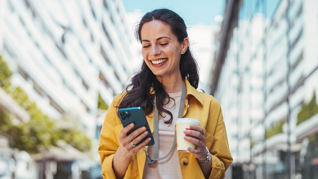 A woman smiling and wearing a strap securing the phone