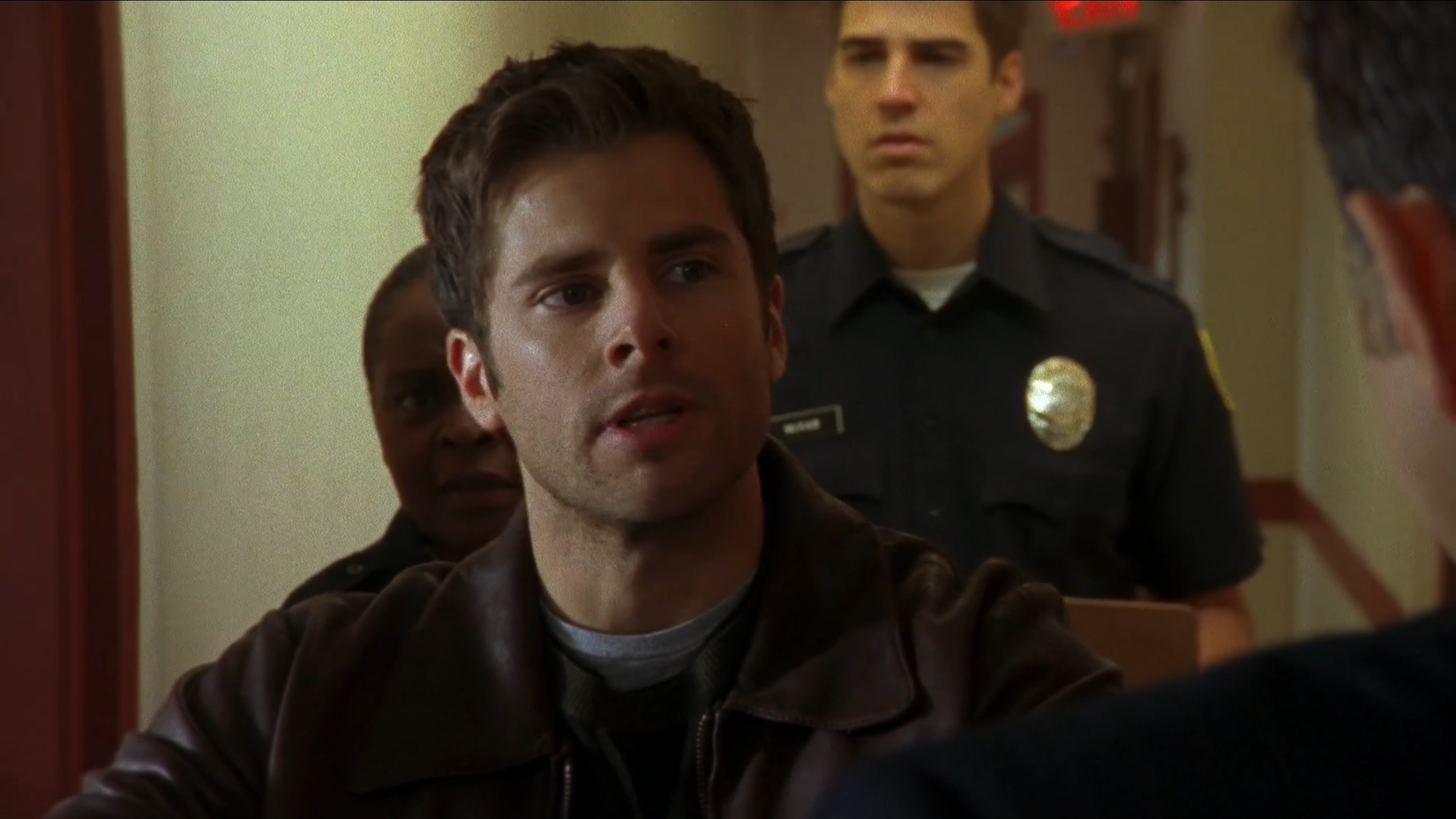 Shawn Spencer from Psych staring with mouth open while a cop stands behind him
