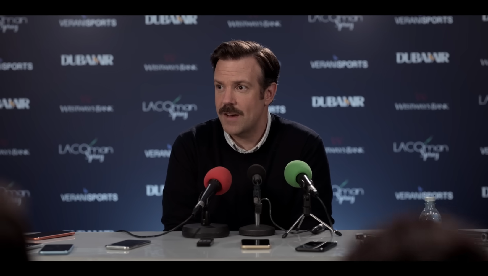 Jason Sudeikis from Ted Lasso smiling at a press conference
