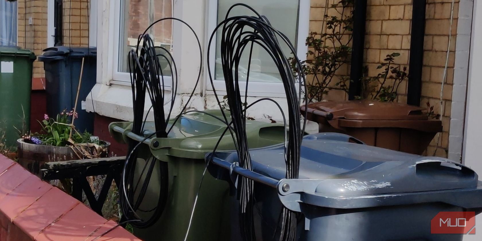 un câble internet fourré dans les poignées d'une poubelle à roulettes