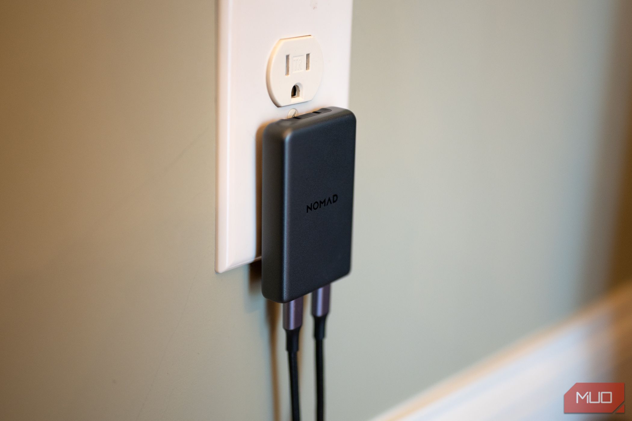 Nomad 65W Slim Power Adapter plugged into a wall outlet with USB-C cables