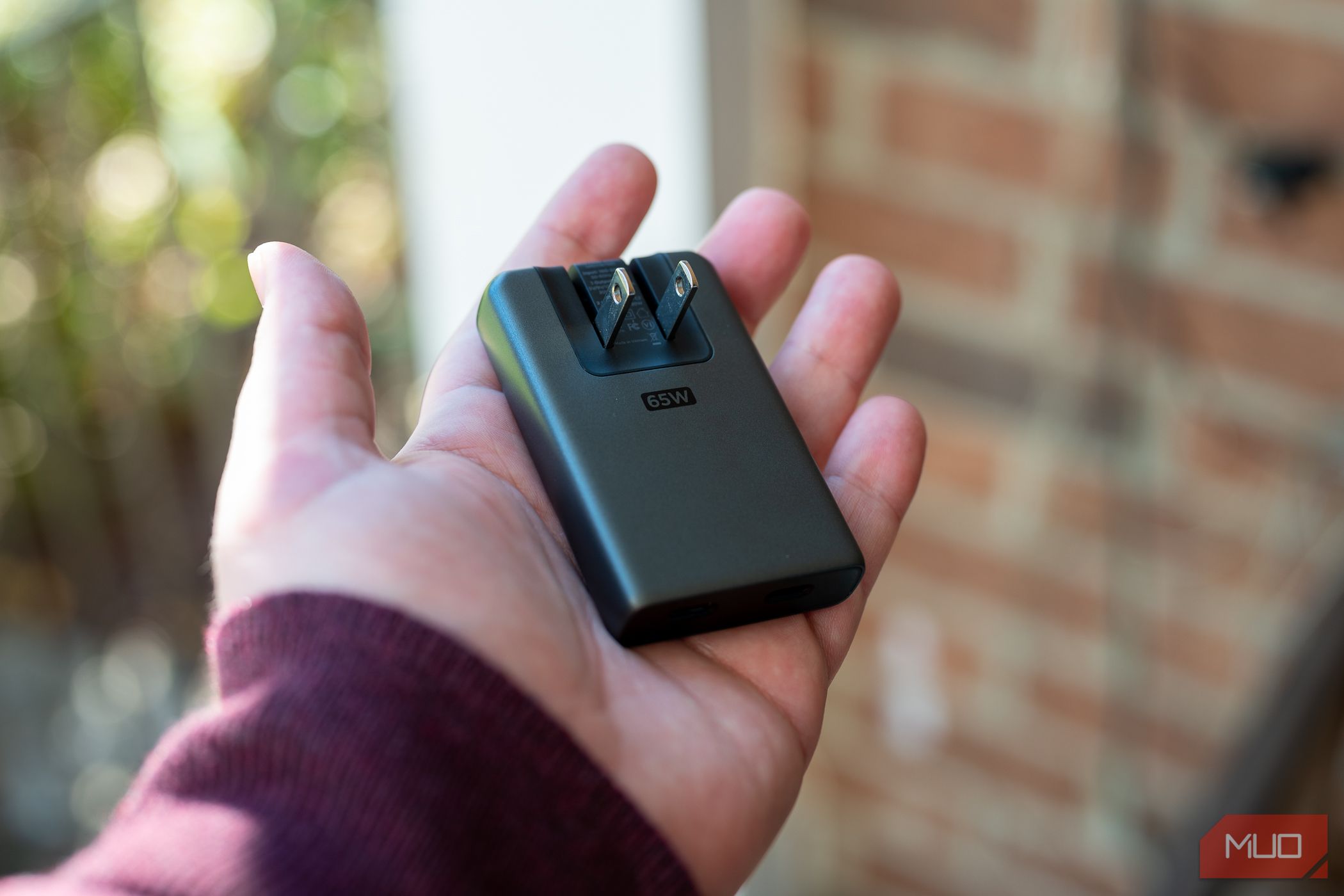 Person holding the Nomad 65W Slim Power Adapter with the prongs extended