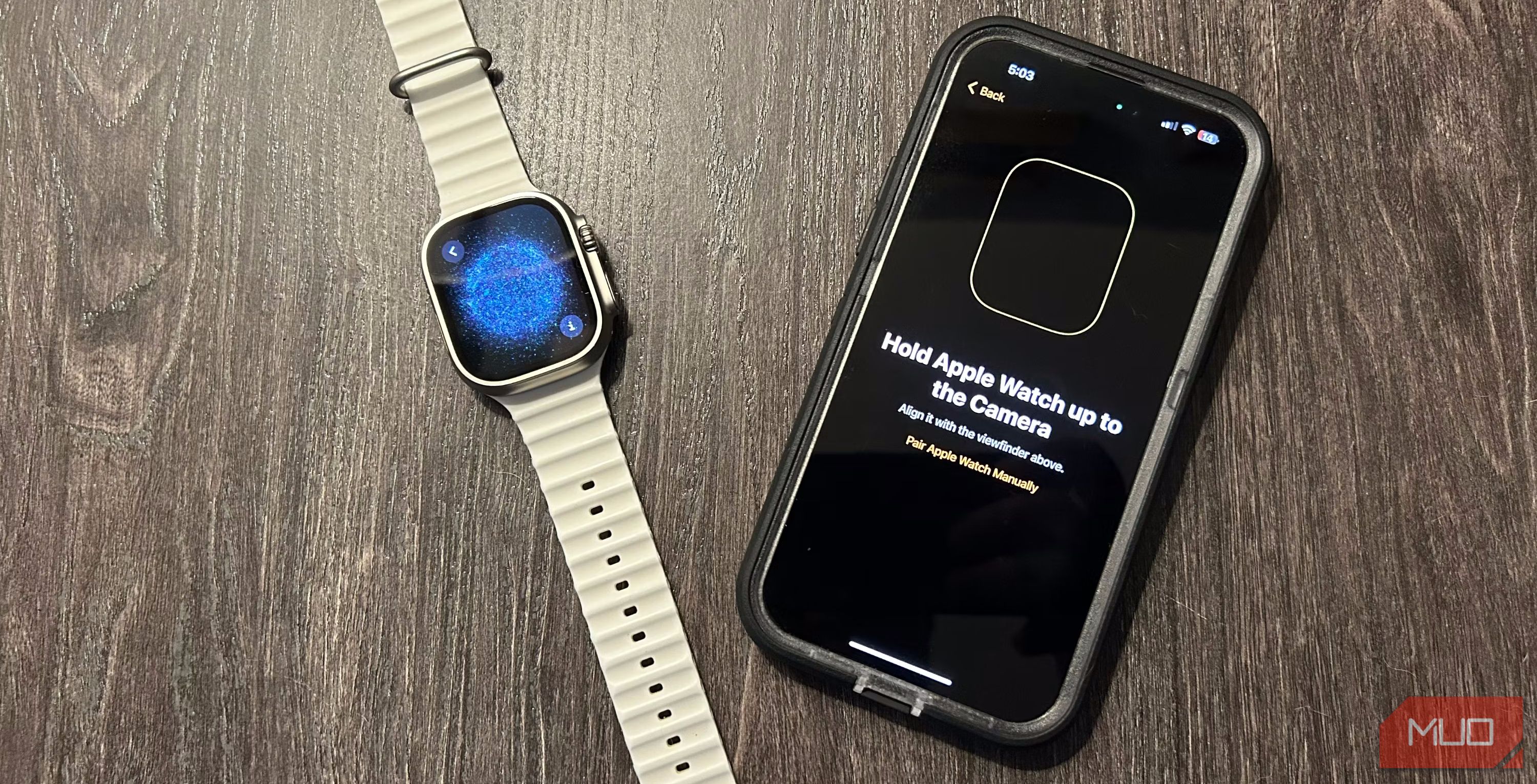 An Apple Watch Ultra showing its pairing screen next to an iPhone on a desk