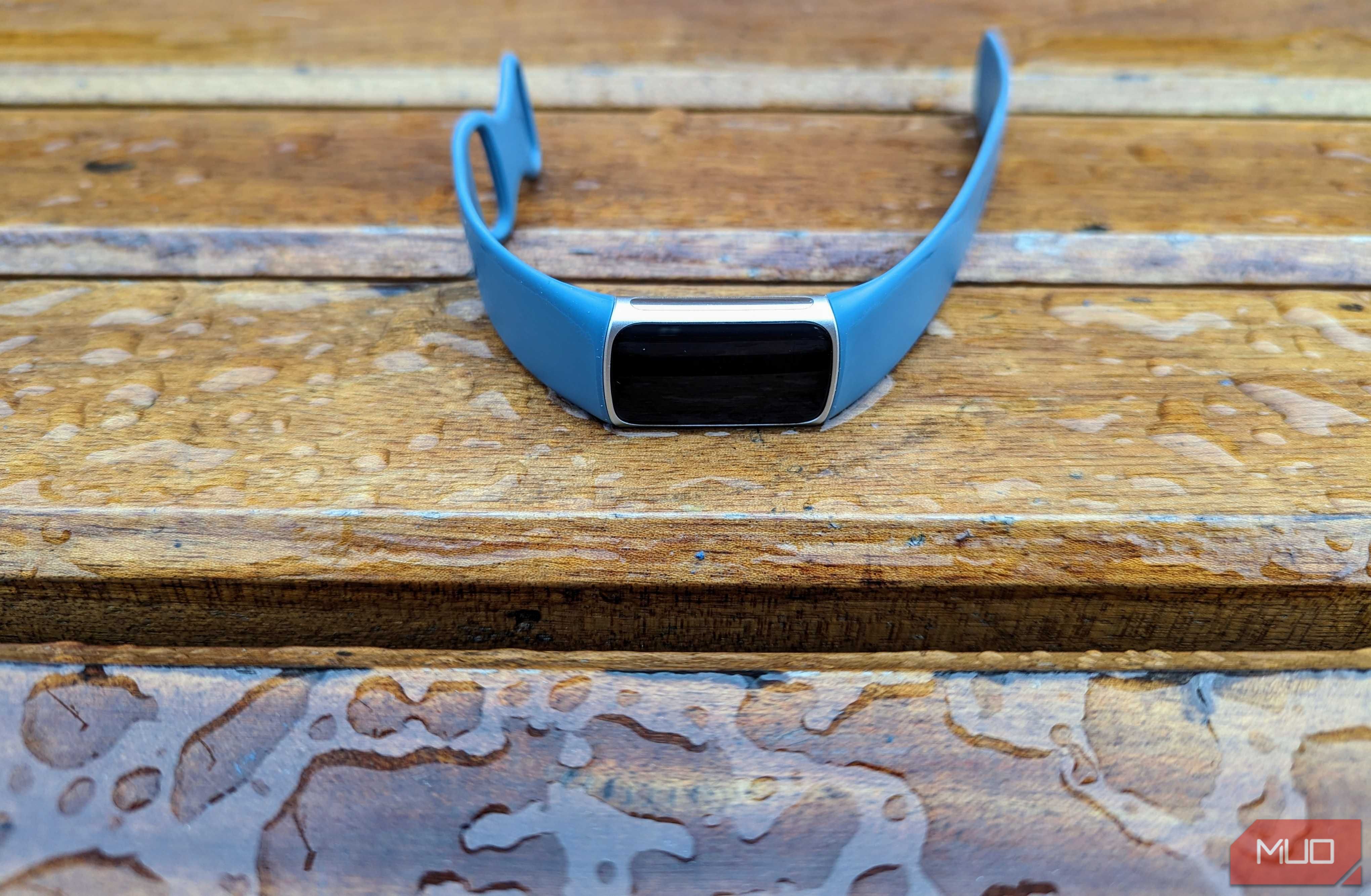 A Fitbit Charge 5 perilously close to a puddle of water