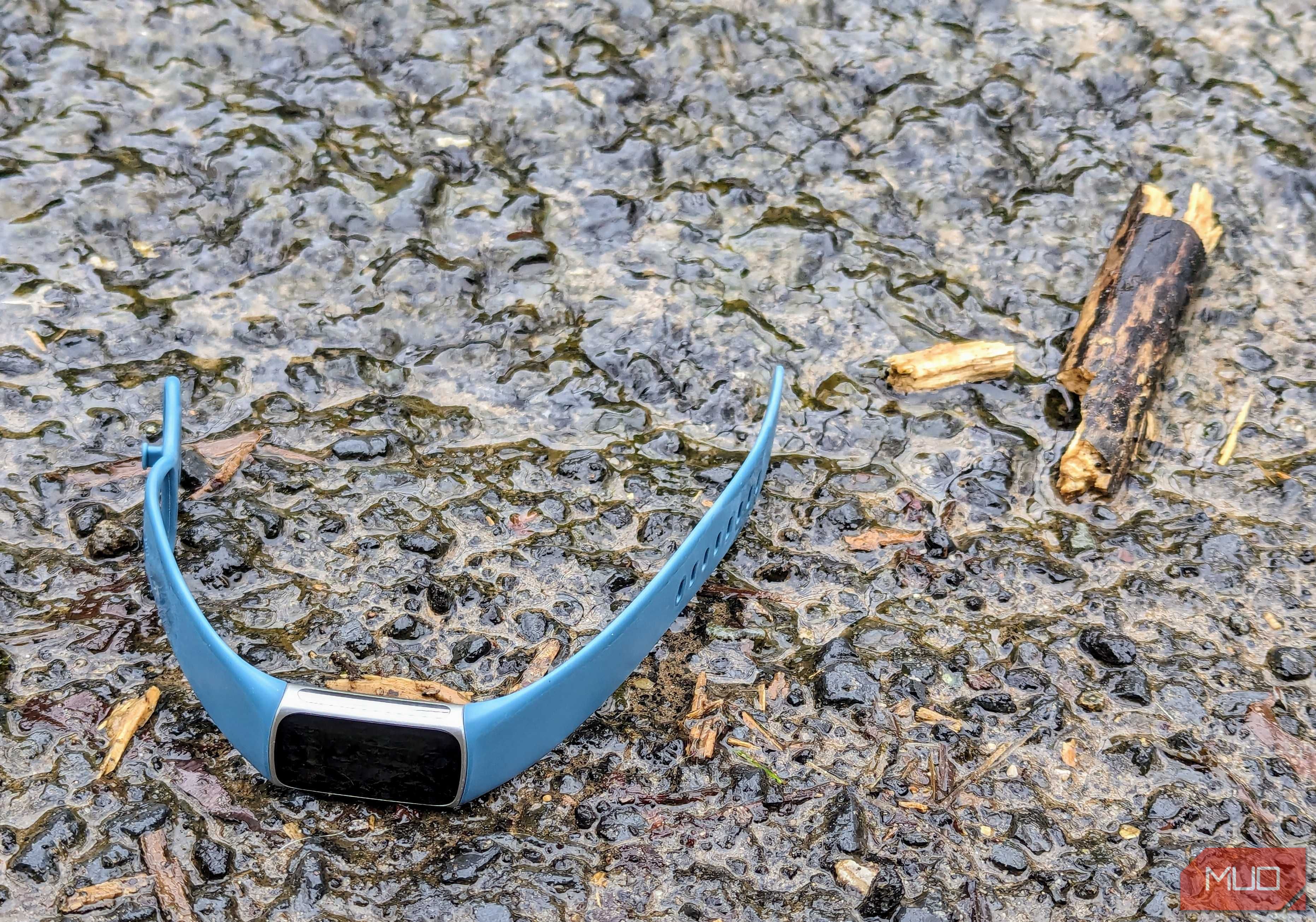 A Fitbit Charge 5 that has fallen next to a stream