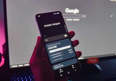 hand holding an Android phone showing the Mobile Hotspot feature in front of a computer monitor